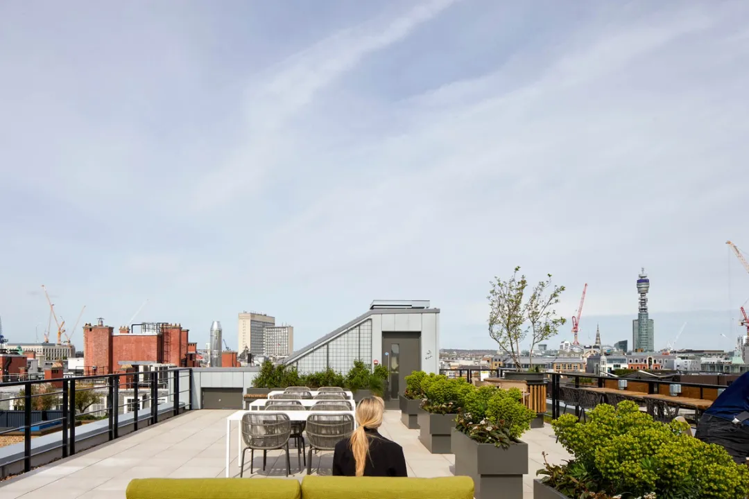 A roof terrace with seating and planting, views of tall buildings