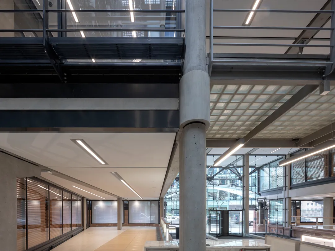 Building entrance seen from inside out to large glass atrium with circular pillar in foreground