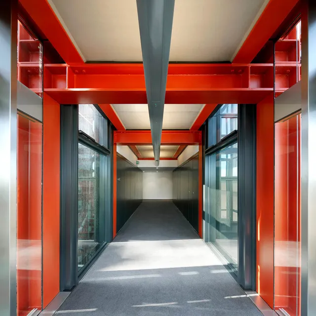 A corridor with red steel beams and glass walls