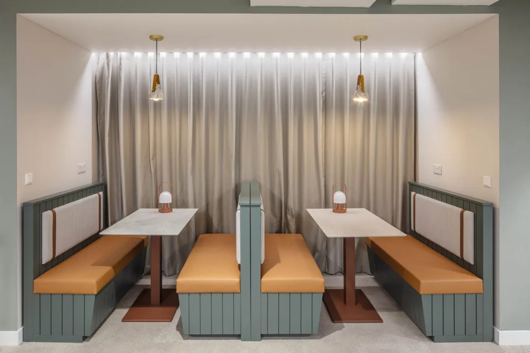 Two booth sofa seats with central tables and pendant lights above