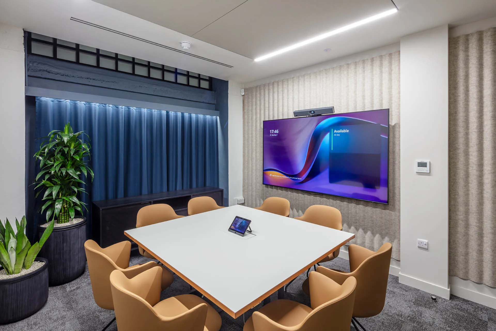 A square table surrounded by orange chairs in a meeting room