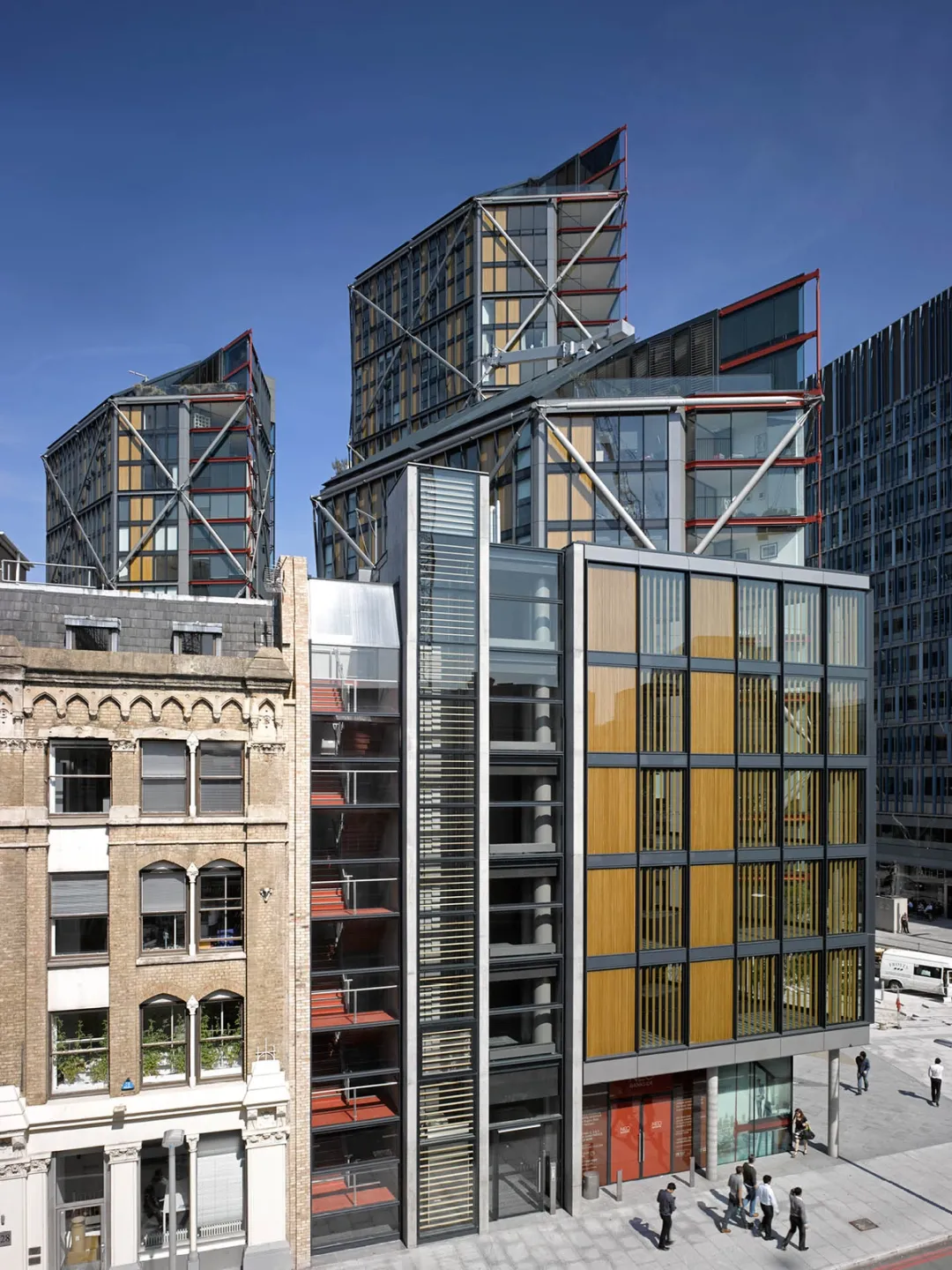 Street view of tall yellow and red glass towers with people walking at base
