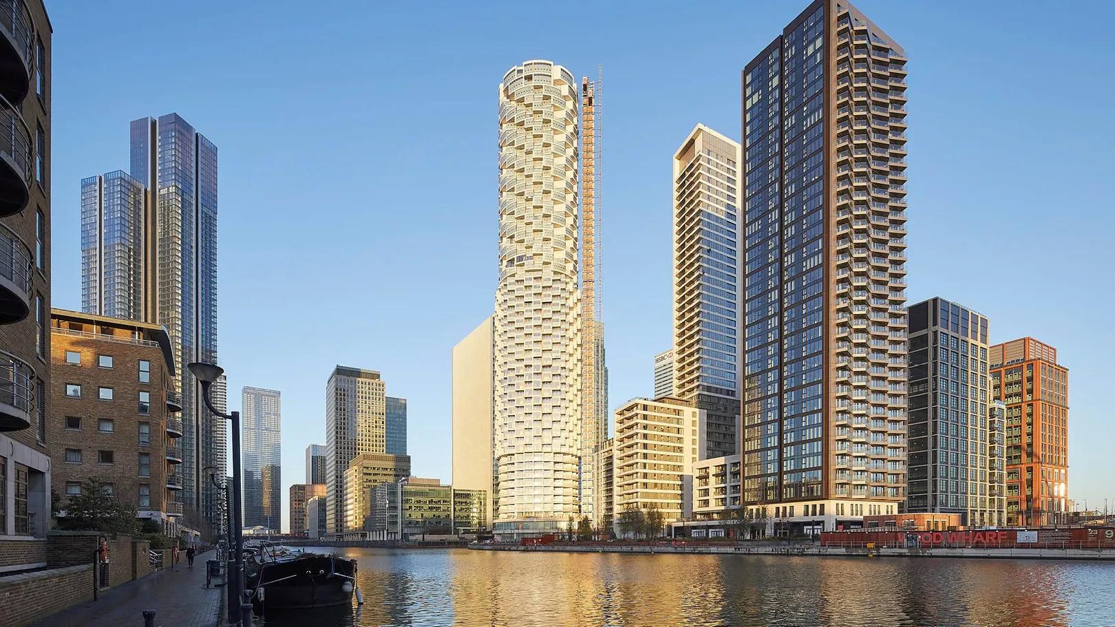 Looking up to tall residential apartment block tower with white exterior, against a blue sky