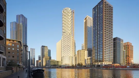 Looking up to tall residential apartment block tower with white exterior, against a blue sky