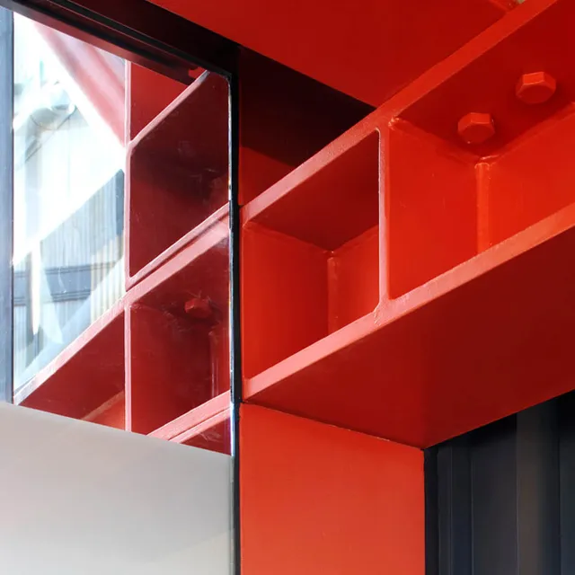Close up of red steel girders adjoining a glass wall