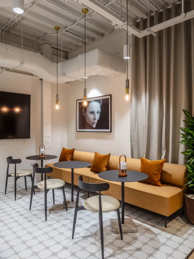 Long orange sofa opposite black round table and chairs