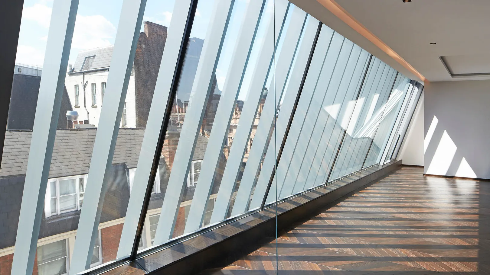 A view looking out of a penthouse window with metal fins and a herringbone dark wood floor