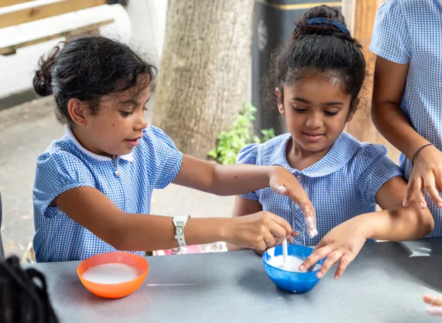 Two girls mixing glue to create a model