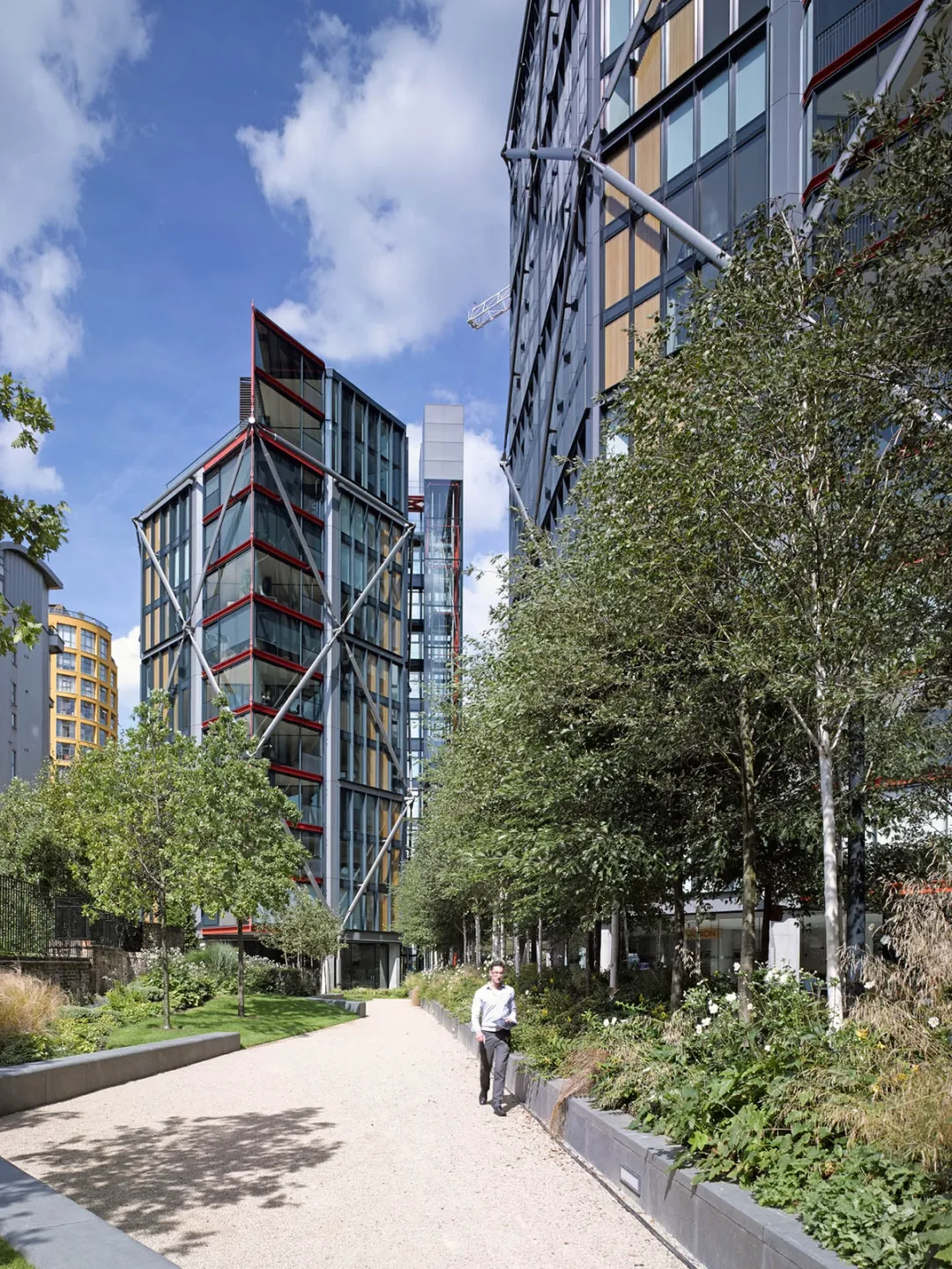 Pathway between residential towers with green planting and trees at borders