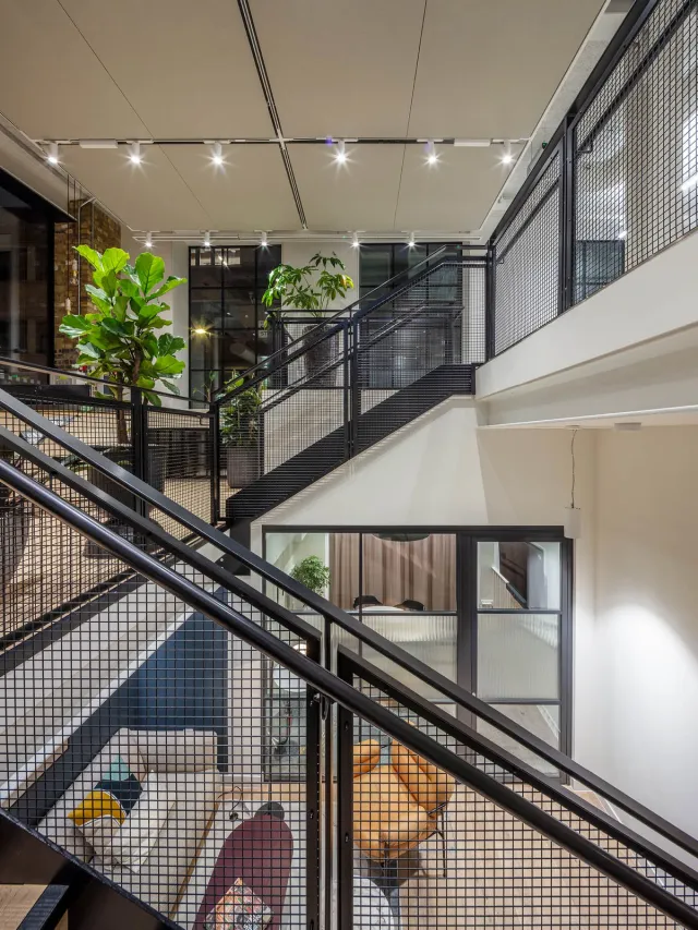 A steel mesh staircase with mezzanine, ground and lower ground office floors in view