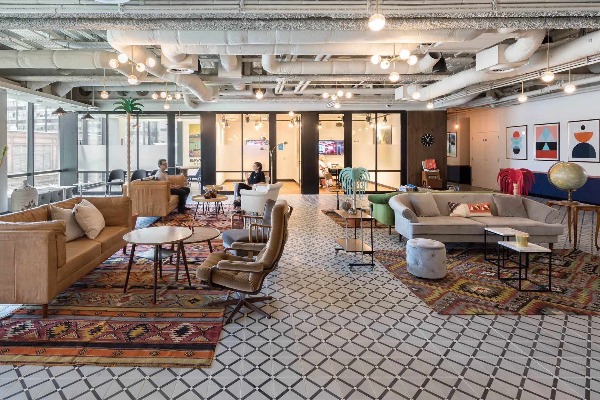 An open office space with clusters of lounge seating and glass meeting rooms behind