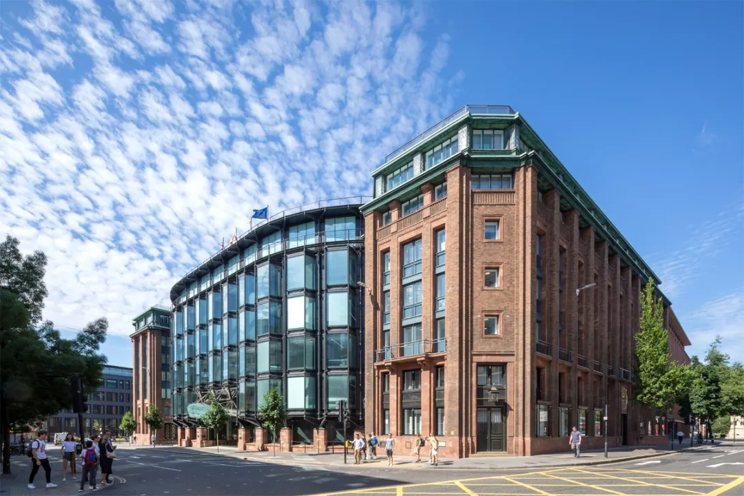 Refurbished building with glass extension against blue sky with some white clouds