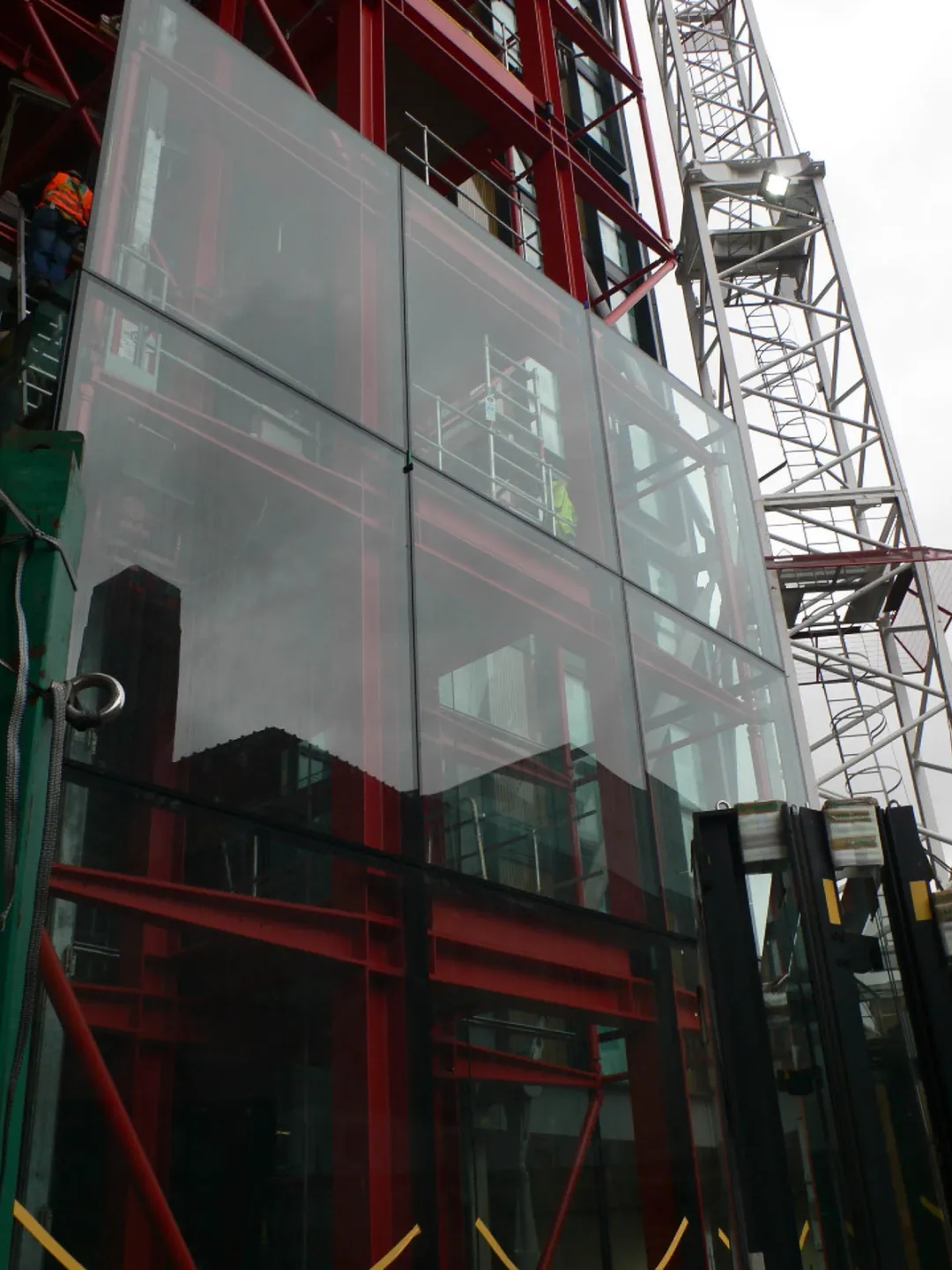 Glass panels being overlaid on red girders
