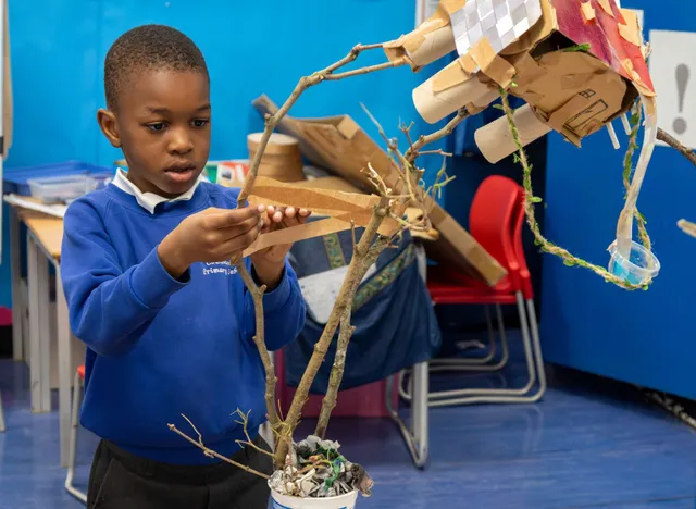 Year 2 pupil adding his model onto tree