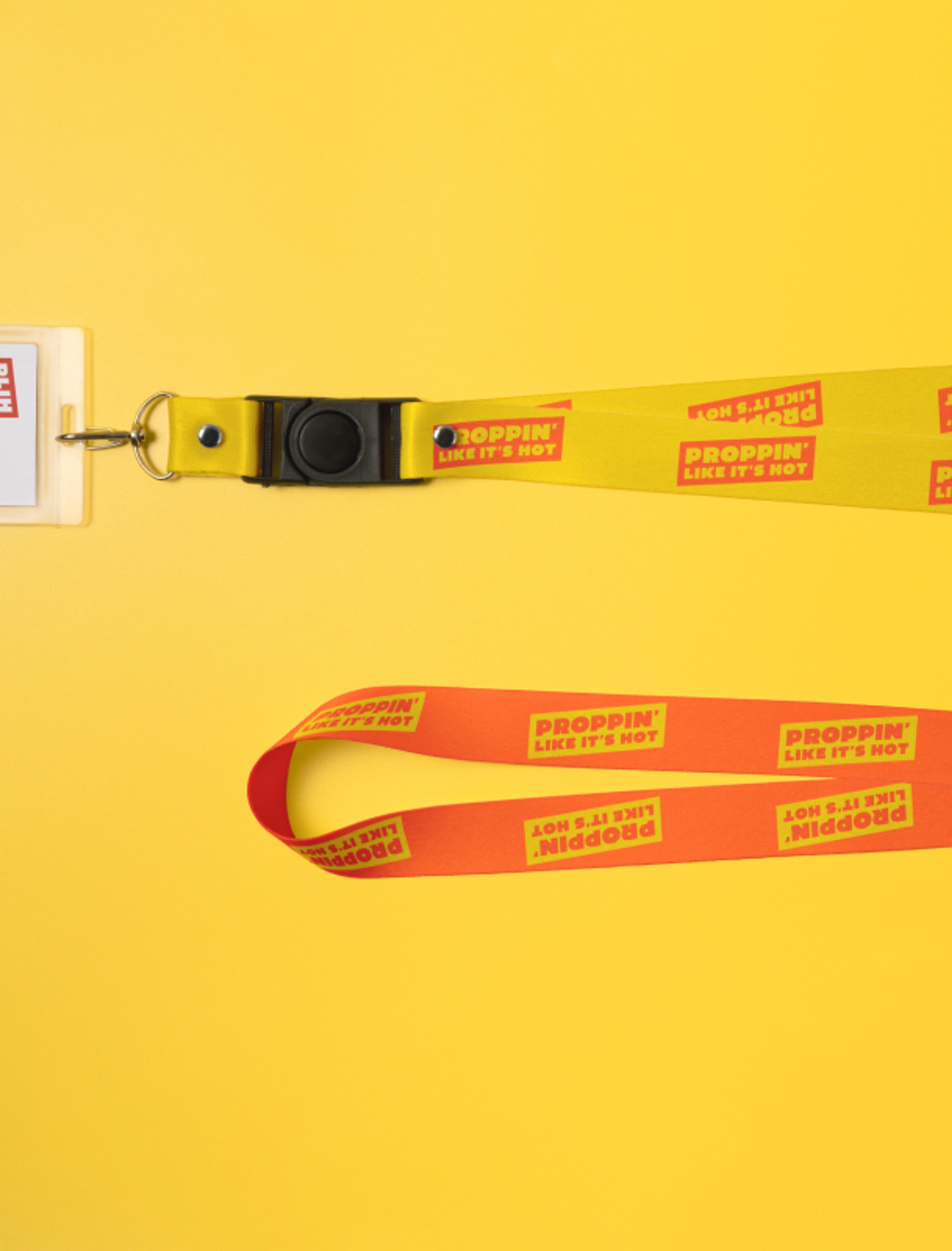 Zwei Schlüsselbänder in Gelb und Rot mit wiederholtem "Proppin’ Like It’s Hot" Schriftzug, vor einem gelben Hintergrund.