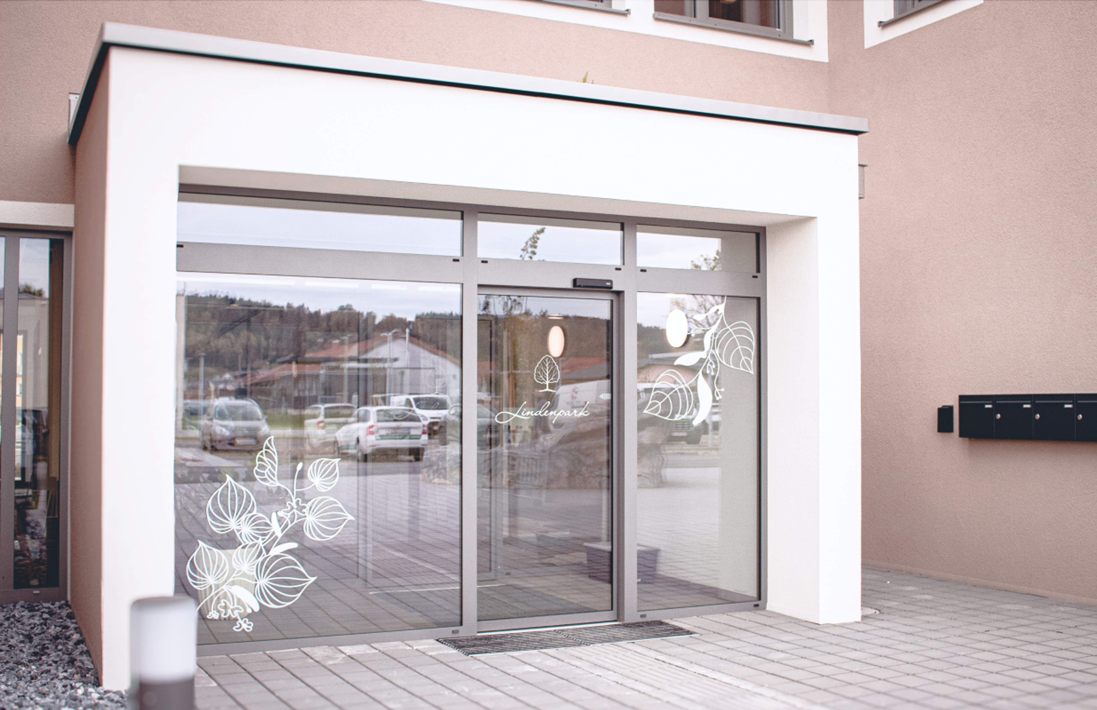 Logo & Grundkonzept BUCHER BRAND MARKETING e.U. Eingangsbereich des Lindenpark Gesundheitszentrums in Gössendorf mit stilvollen Fensterfolien und floralen Mustern, entworfen im Rahmen des Branding-Konzepts von Unerwartet Design.