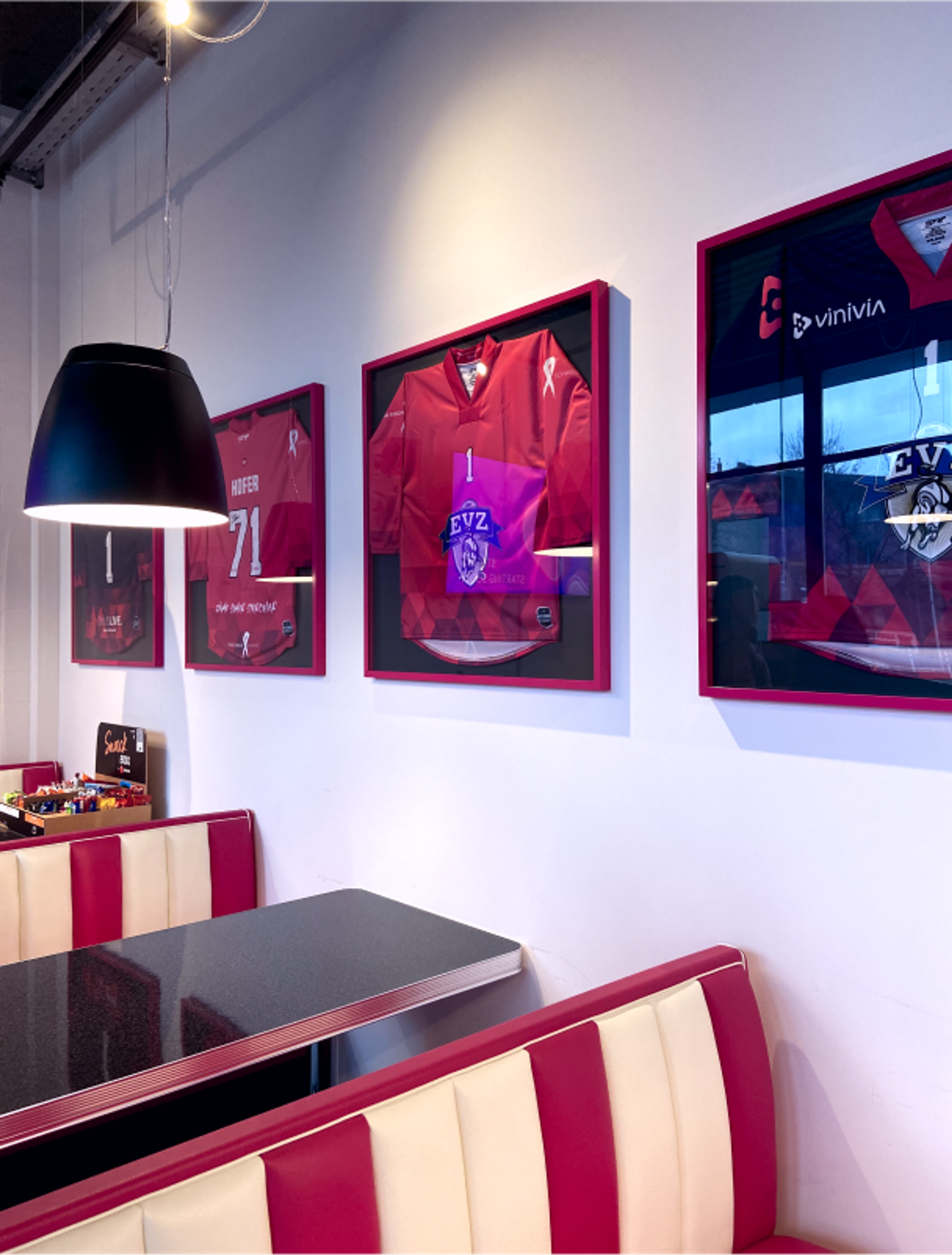 Design-Wand im Vinivia-Büro in der Schweiz mit eingerahmten Hockey-Trikots des EVZ-Teams als stilvolle Wanddekoration – Unerwartet Design