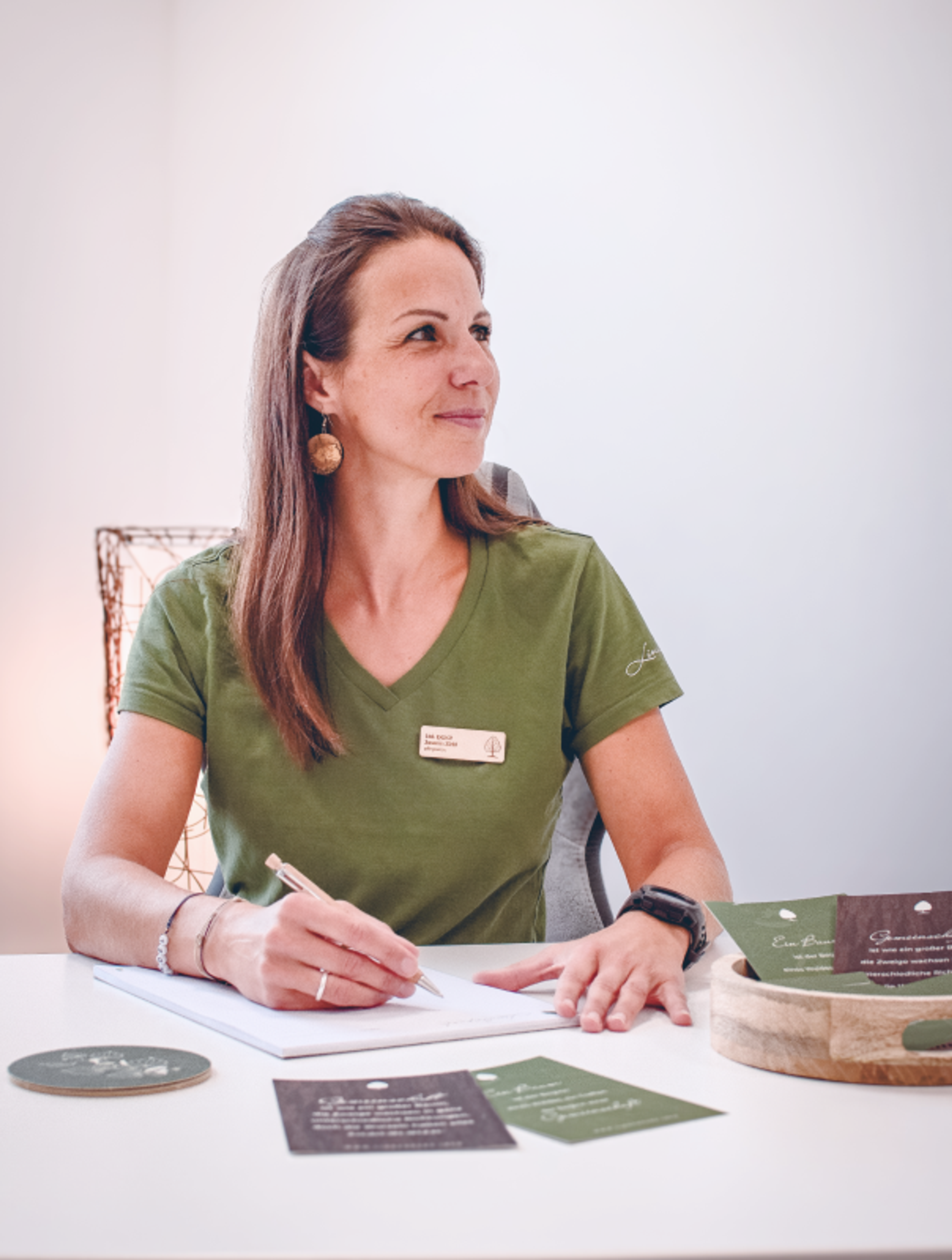 Logo & Grundkonzept BUCHER BRAND MARKETING e.U. Managerin des Lindenpark Gesundheitszentrums am Schreibtisch mit gestalteten Printmaterialien, die das moderne und harmonische Design von Unerwartet Design zeigen.