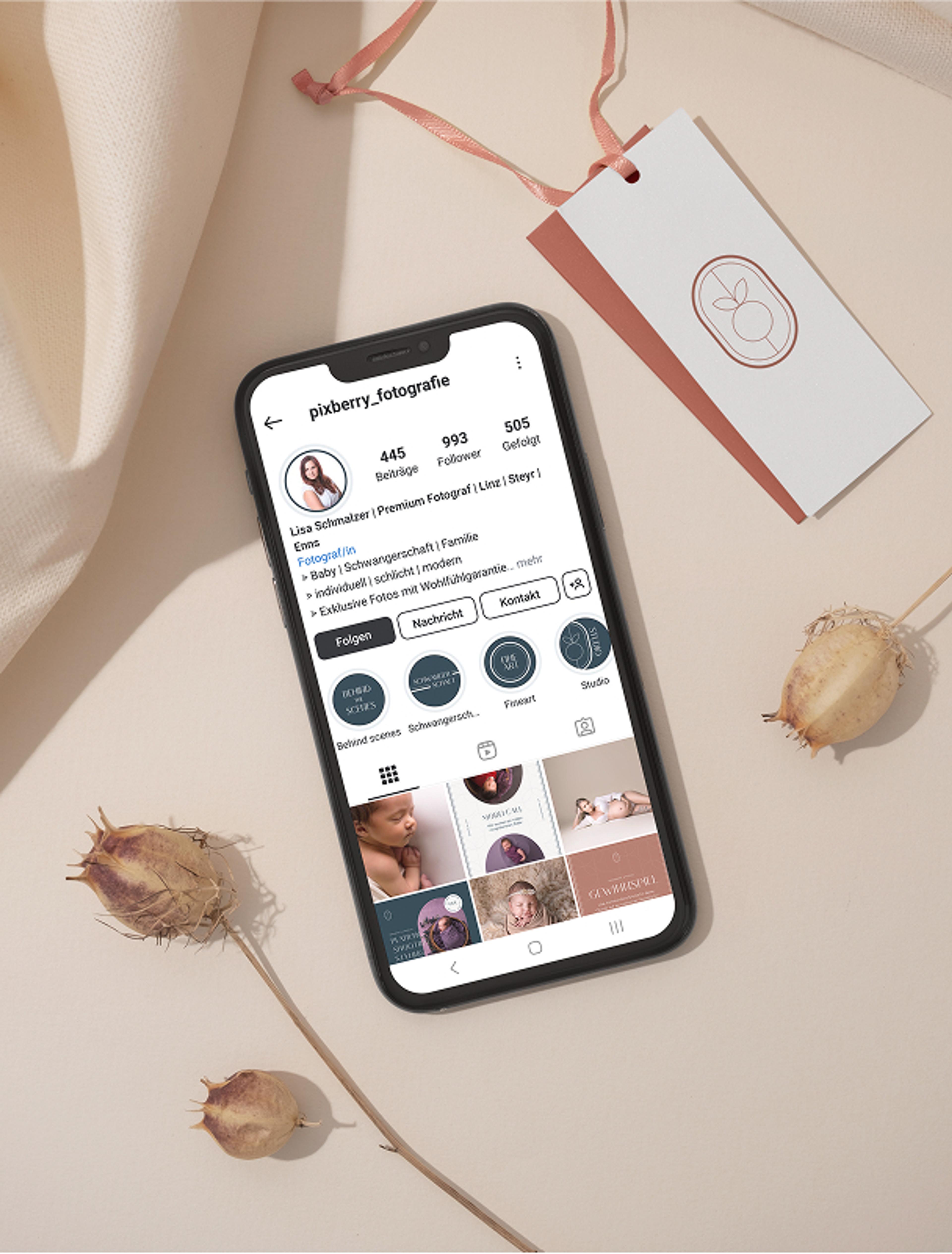 Smartphone mit Pixberry Instagram-Seite und passendem Branding-Tag – Ein Handy mit geöffneter Pixberry Instagram-Seite liegt neben einem Branding-Tag mit dem Pixberry-Logo, umgeben von getrockneten Mohnkapseln.