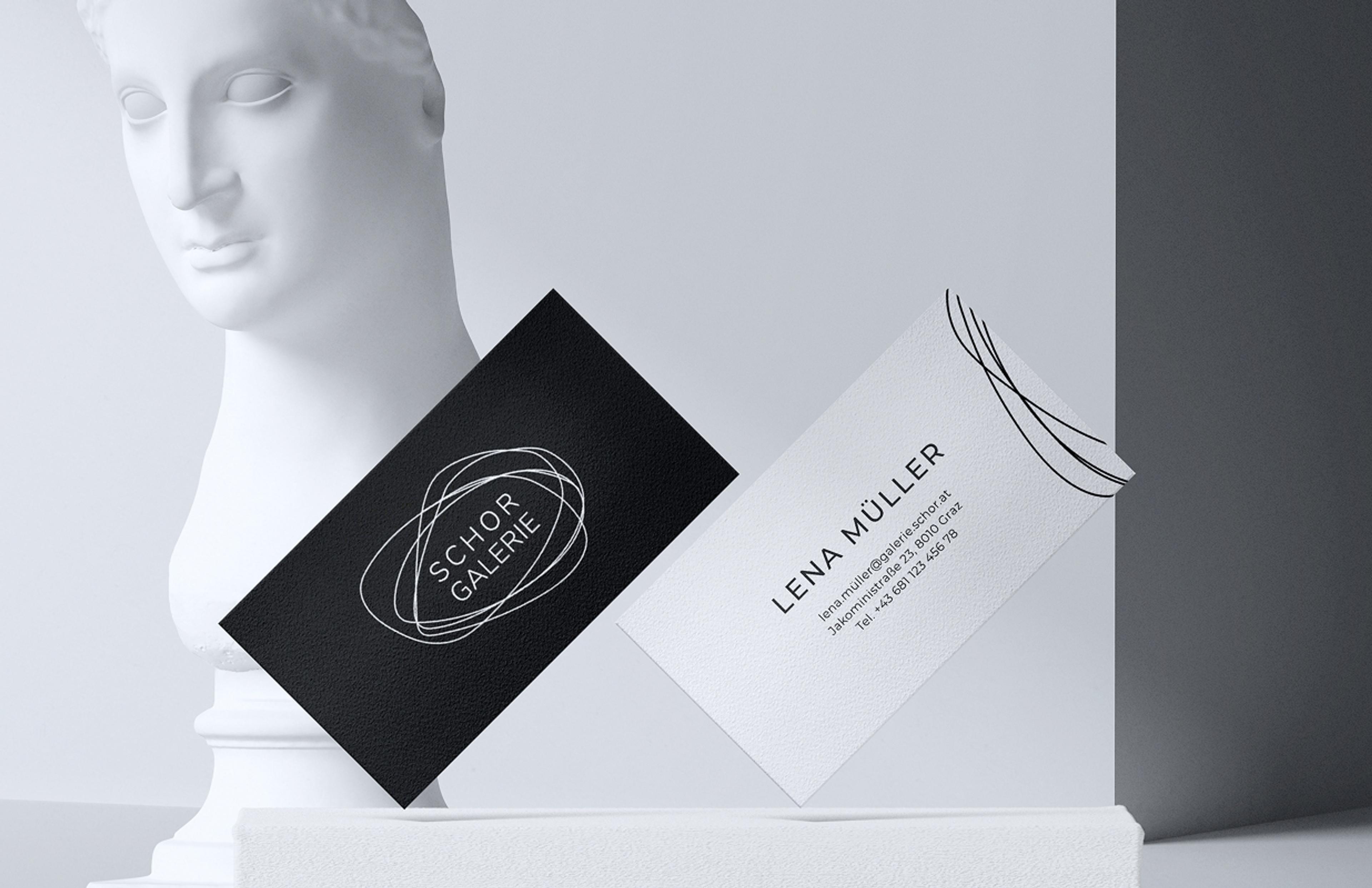 Zwei stilvolle Visitenkarten in Schwarz-Weiß, mit dem Schor Galerie Logo, elegant inszeniert vor einer klassischen Büste.
