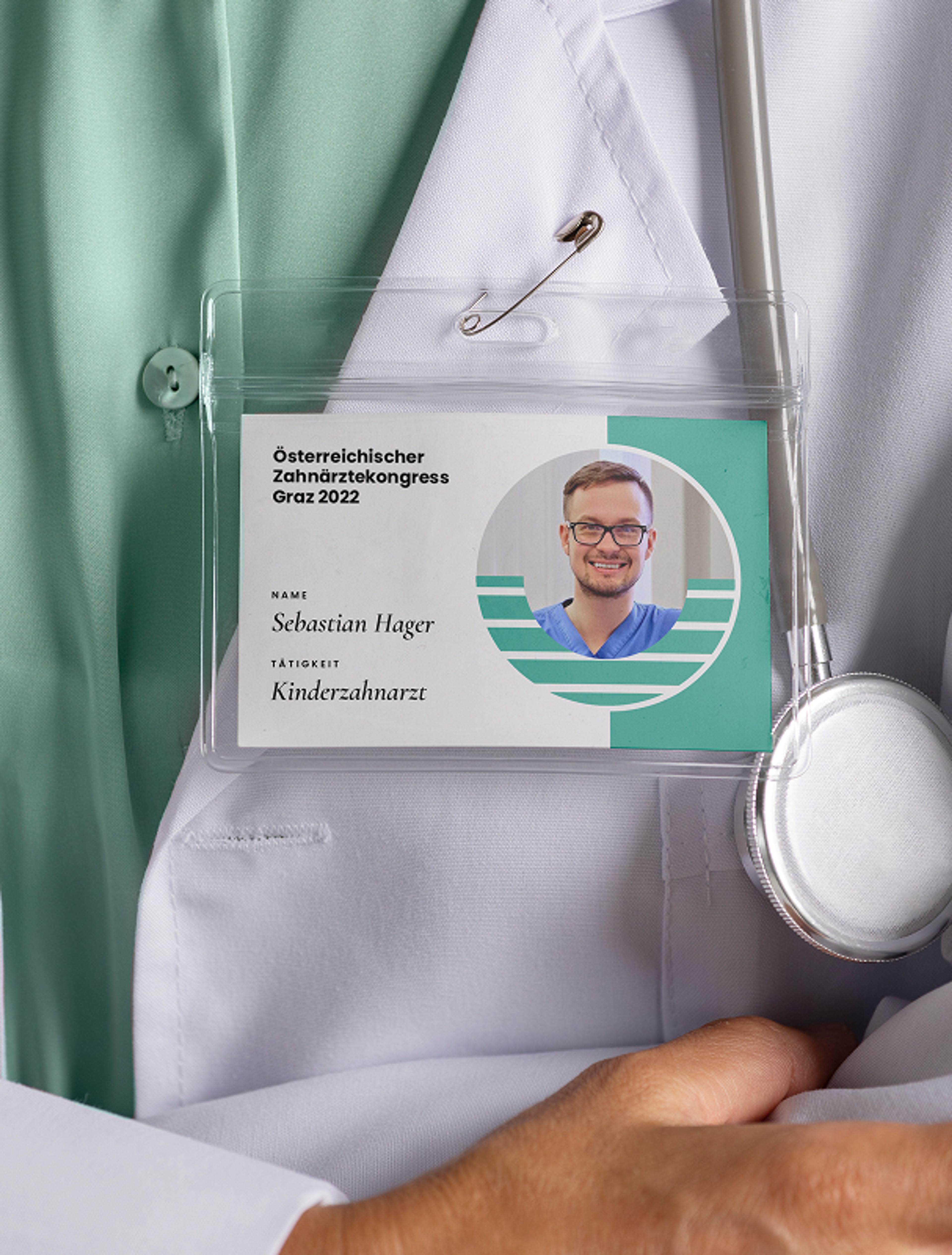 Namensschild für Dr. Sebastian Hager, Kinderzahnarzt, beim Österreichischen Zahnärztekongress Graz 2022, befestigt an einem weißen Arztkittel mit Stethoskop, gestaltet von Unverwartet Design.