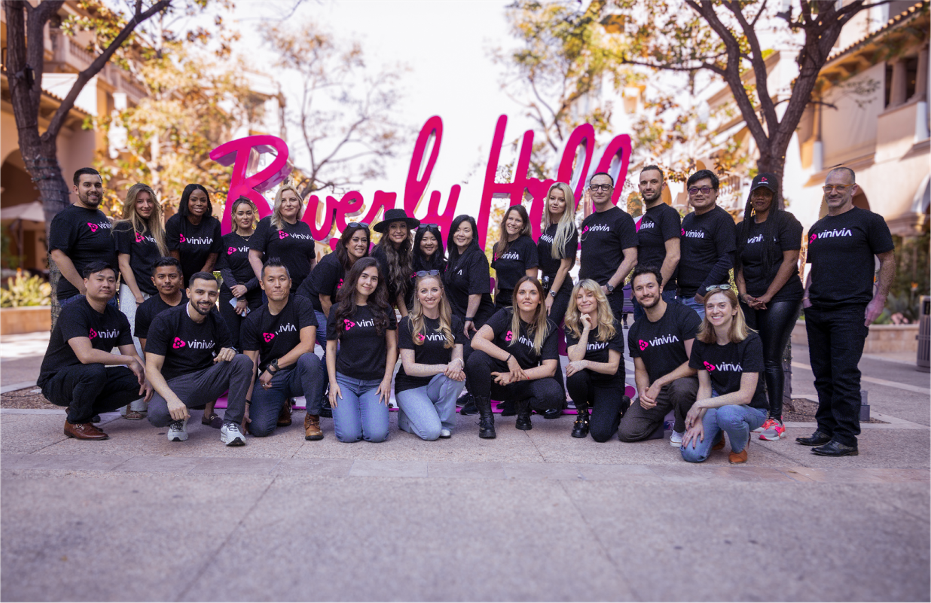 Gruppenfoto des Vinivia-Teams vor dem Beverly Hills Schriftzug, alle in schwarzen T-Shirts mit Vinivia-Logo, sonniger Hintergrund mit Bäumen – Unerwartet Design