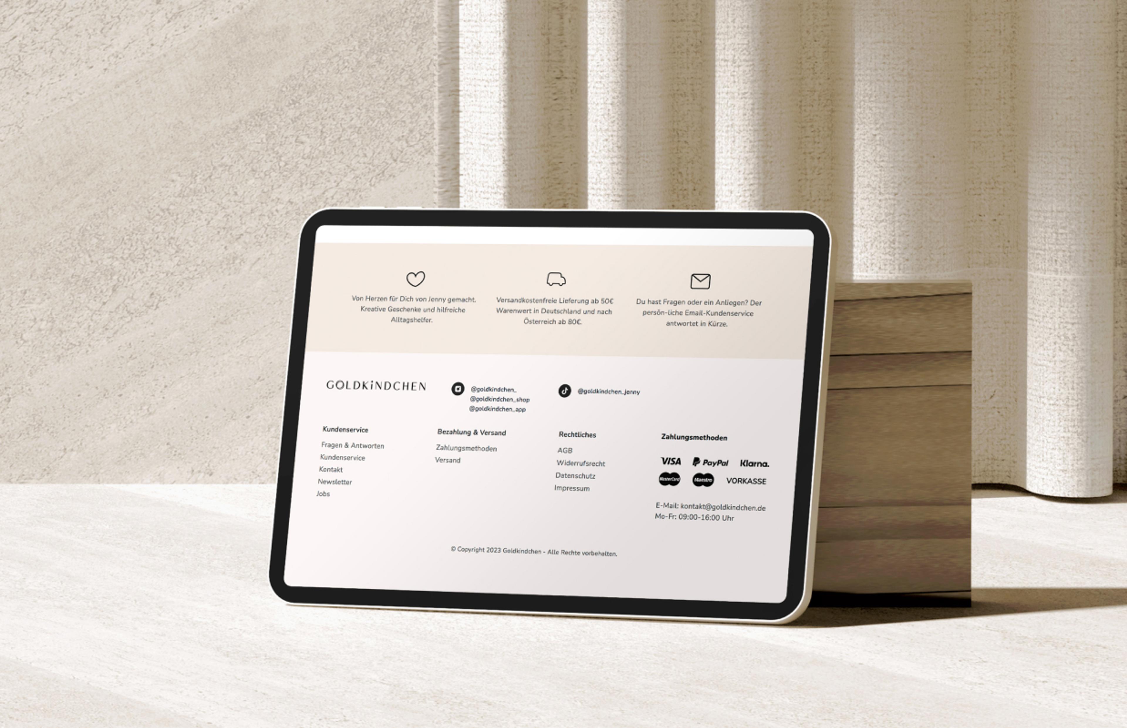 Footer-Design des Goldkindchen-Webshops auf einem iPad, mit Kundenservice-Infos, Zahlungsmethoden und Social-Media-Links, gestaltet von Unerwartet Design in Graz.