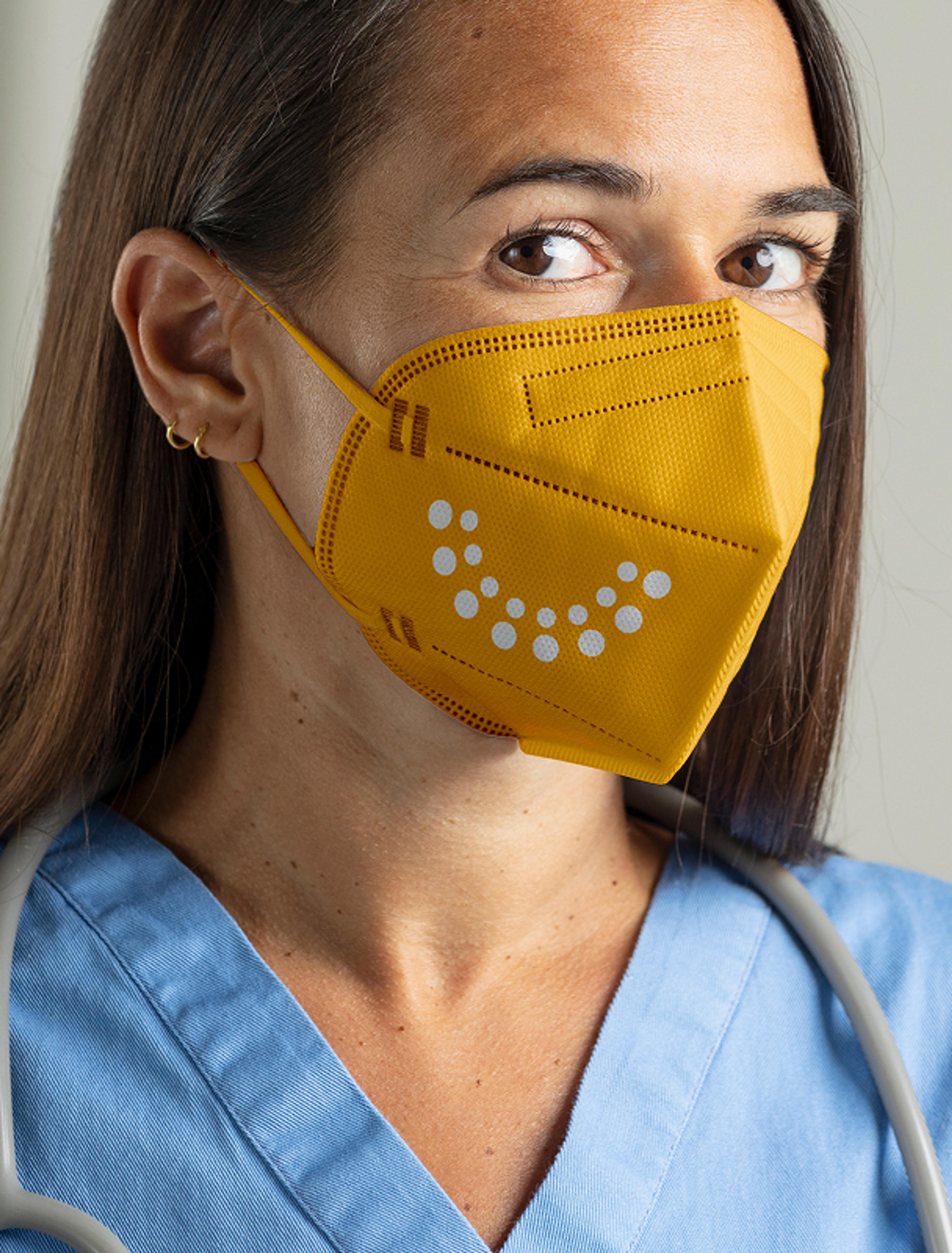 Nahaufnahme einer Ärztin mit einer gelben FFP2-Maske, bedruckt mit dem Halbkreis-Logo des Österreichischen Zahnärztekongresses Graz 2022, Design von Unverwartet Design.