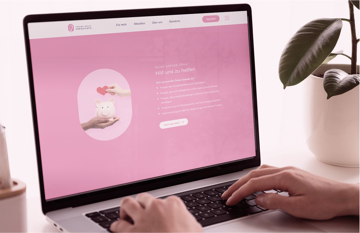 Ein Laptop zeigt das Spendenformular der Zauberfrauen-Website. Eine Hand tippt auf die Tastatur, das Design ist in Rosa gehalten.