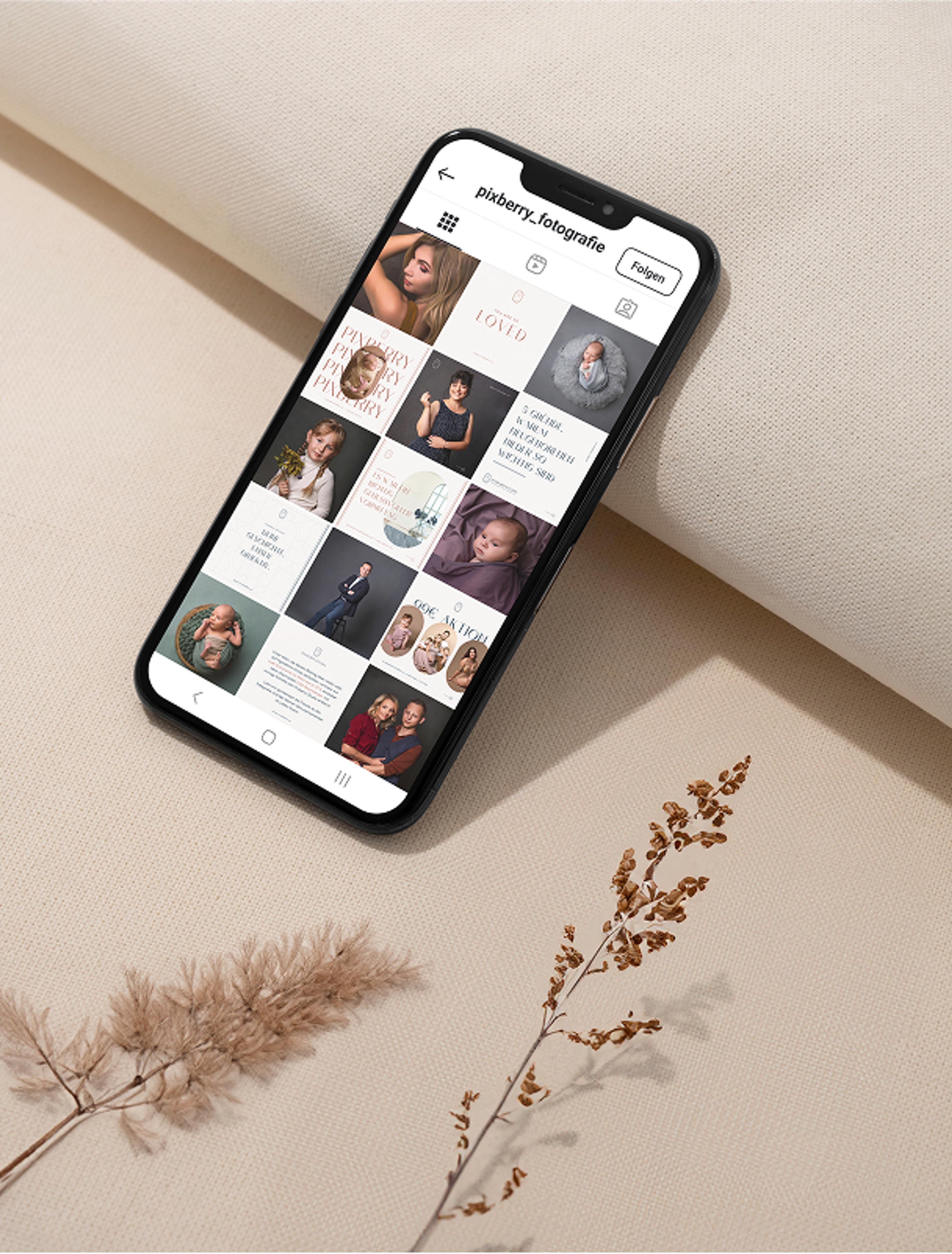 Smartphone mit Pixberry Instagram-Feed, umgeben von Naturtönen – Ein Handy auf hellem Stoff zeigt den harmonischen Instagram-Feed von Pixberry Fotografie, eingerahmt von Trockenblumen.