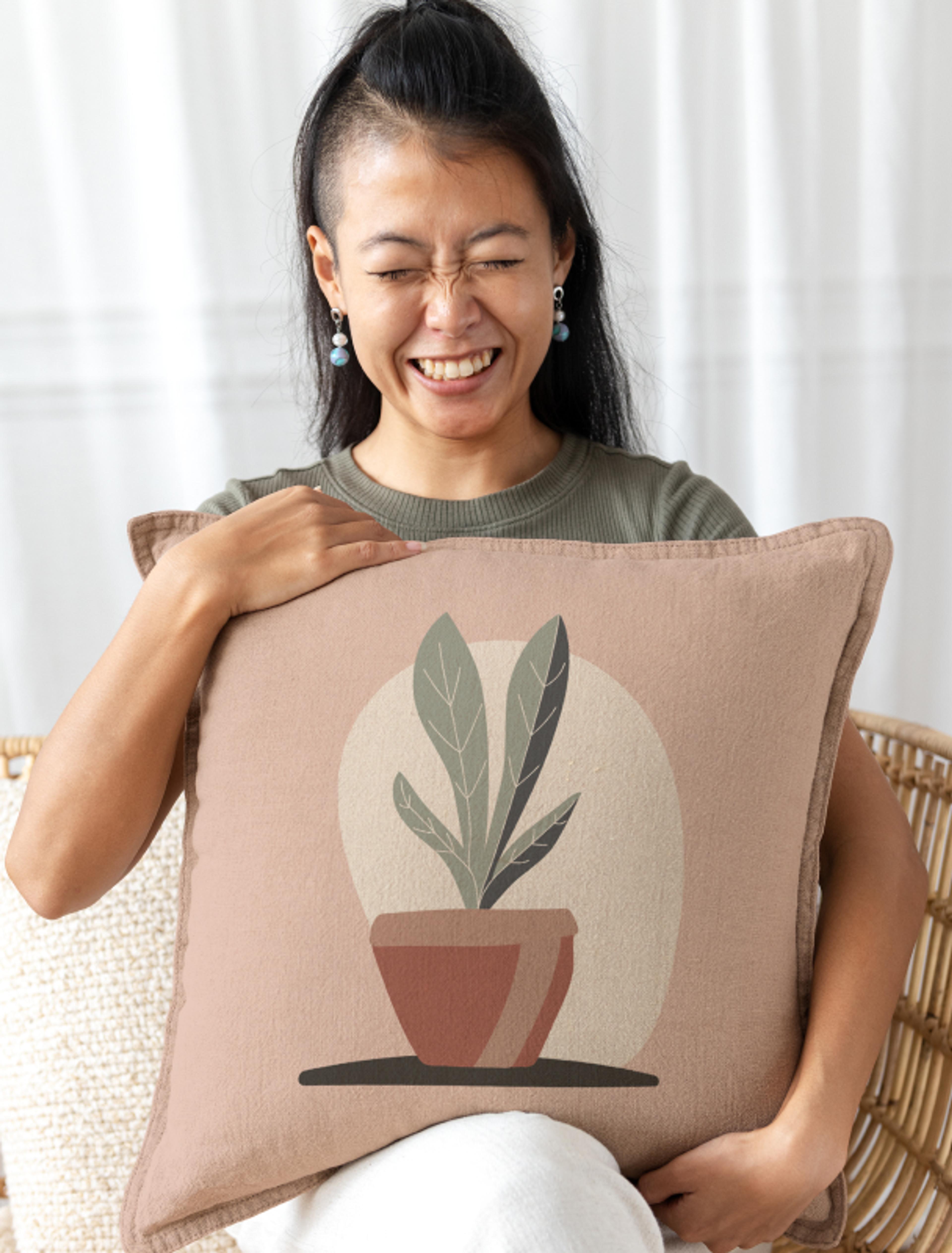 Glückliche Frau mit dekorativem Kissen mit Pflanzenmotiv in einem Rattansessel, natürlich und hochwertig – Teil des illustrativen Brandings für Rattatat durch Unerwartet Design.