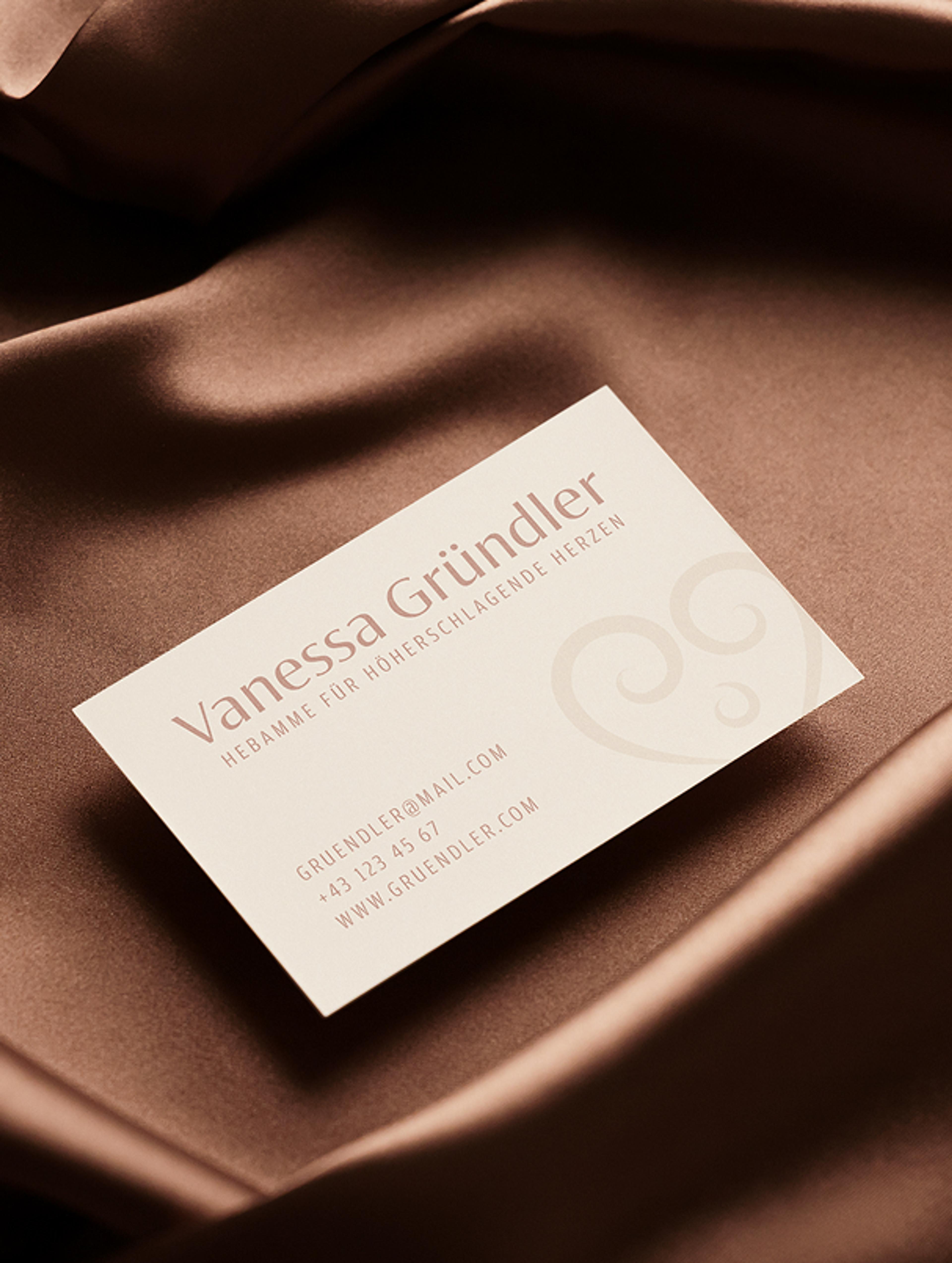Elegante Visitenkarte von Hebamme Vanessa Gründler mit Herzsymbol und warmen Erdtönen. Branding von Unerwartet Design, das Vertrauen & Geborgenheit vermittelt.