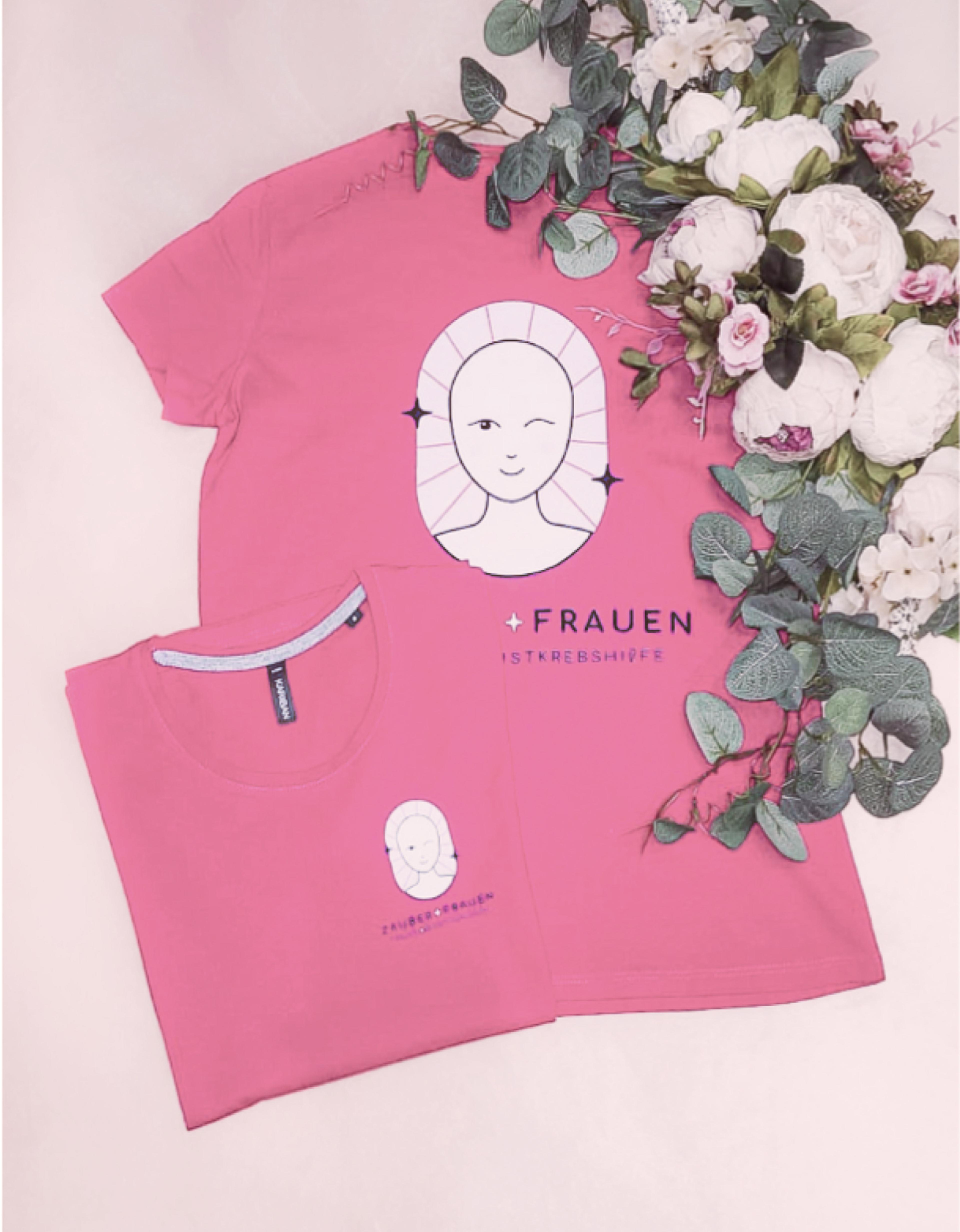 Zwei pinke T-Shirts mit dem Zauberfrauen-Logo, elegant arrangiert mit Blumen. Das Design symbolisiert weibliche Stärke und den Kampf gegen Brustkrebs. - Unerwartet Design