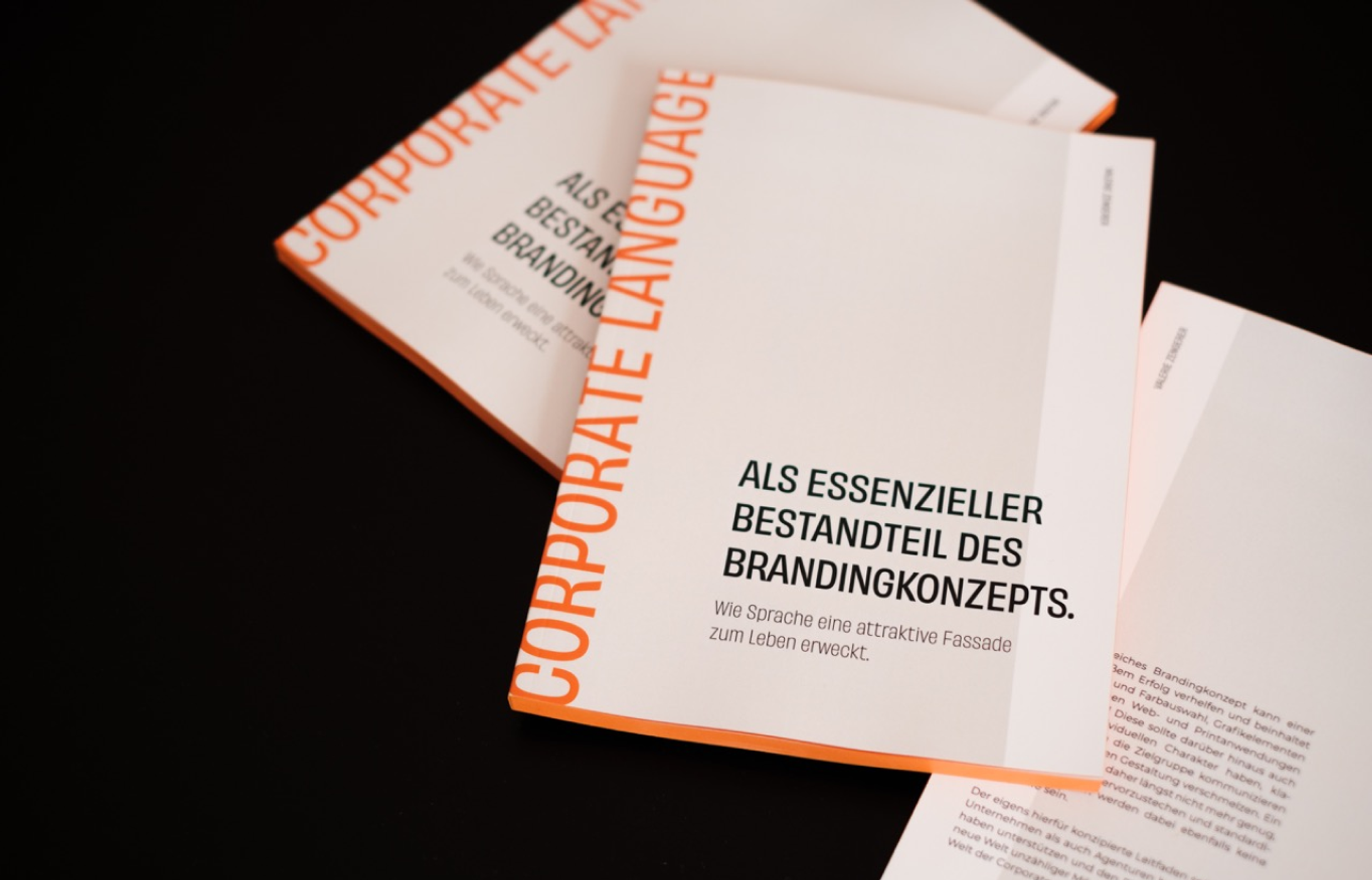 Gedruckte Broschüren des Corporate Language Leitfadens von Unerwartet Design auf schwarzem Hintergrund.