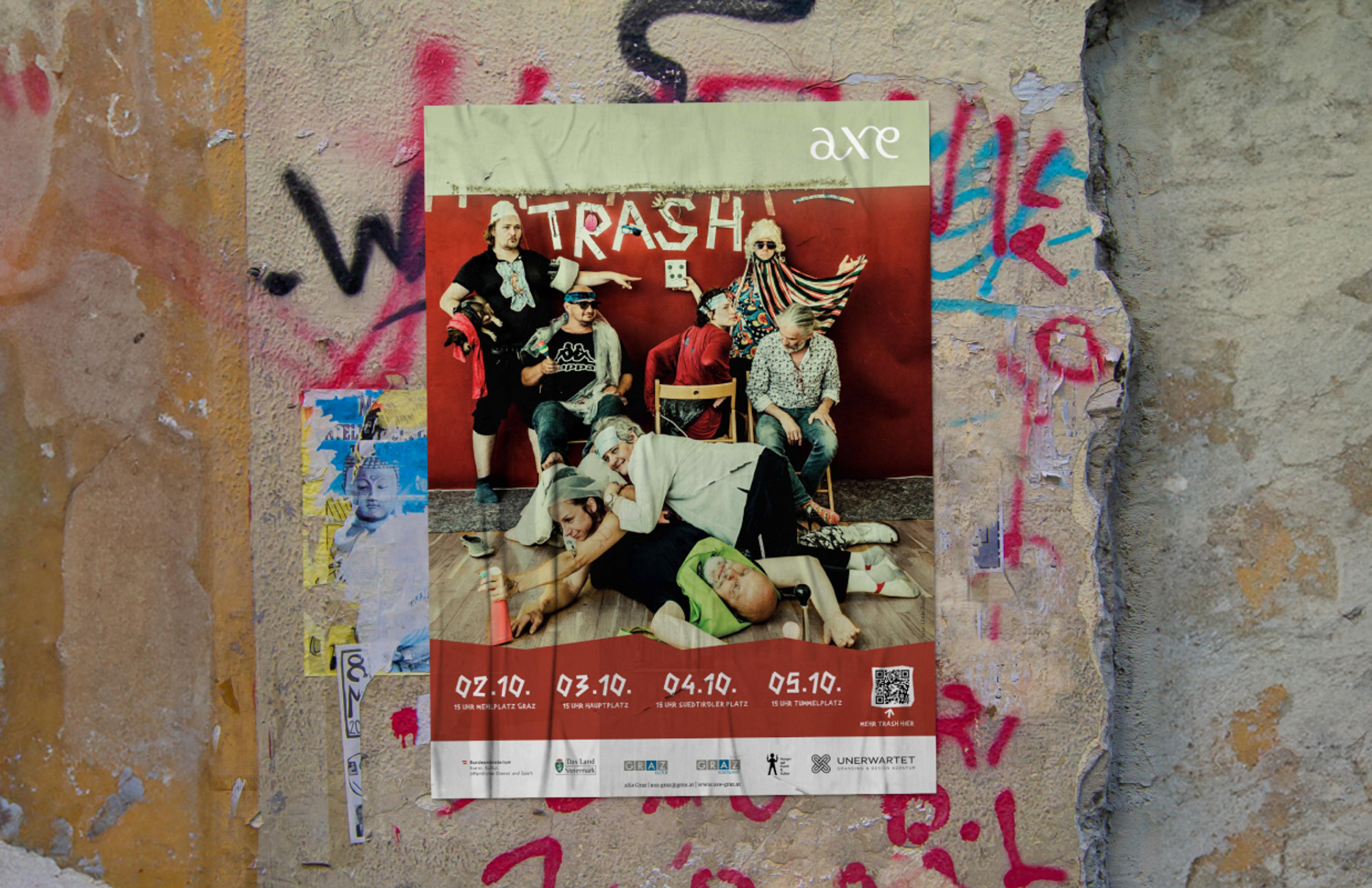 Plakat für das Theaterstück "Trash" an einer Graffiti-Wand – Ein lebhaft gestaltetes Plakat mit einer chaotischen Szene, befestigt an einer urbanen, bemalten Wand.