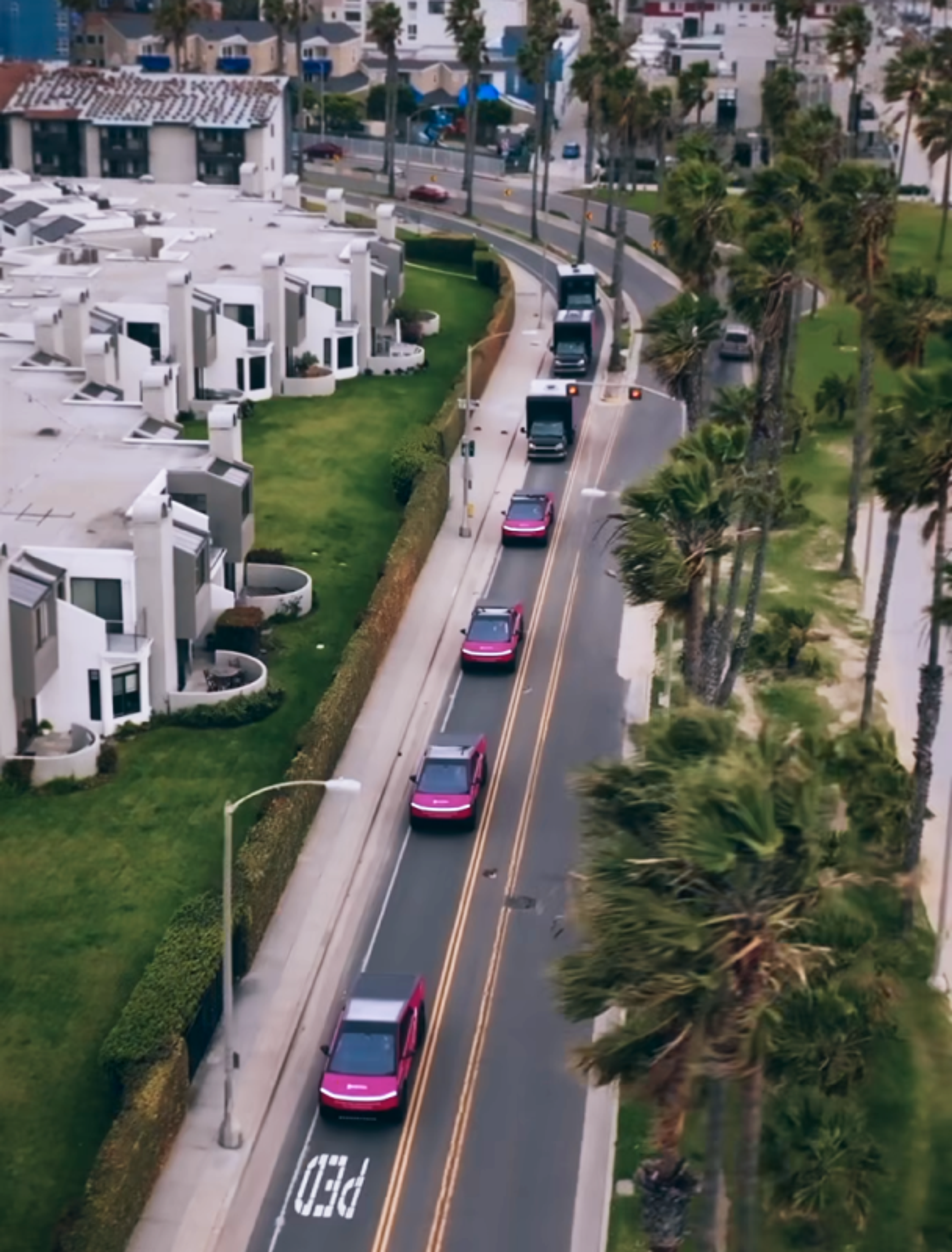 Foto: Vinivia Luftaufnahme von Vinivia-Werbefahrzeugen auf einer Straße, die sich durch eine moderne Wohnanlage mit Palmen schlängelt - Unerwartet Design