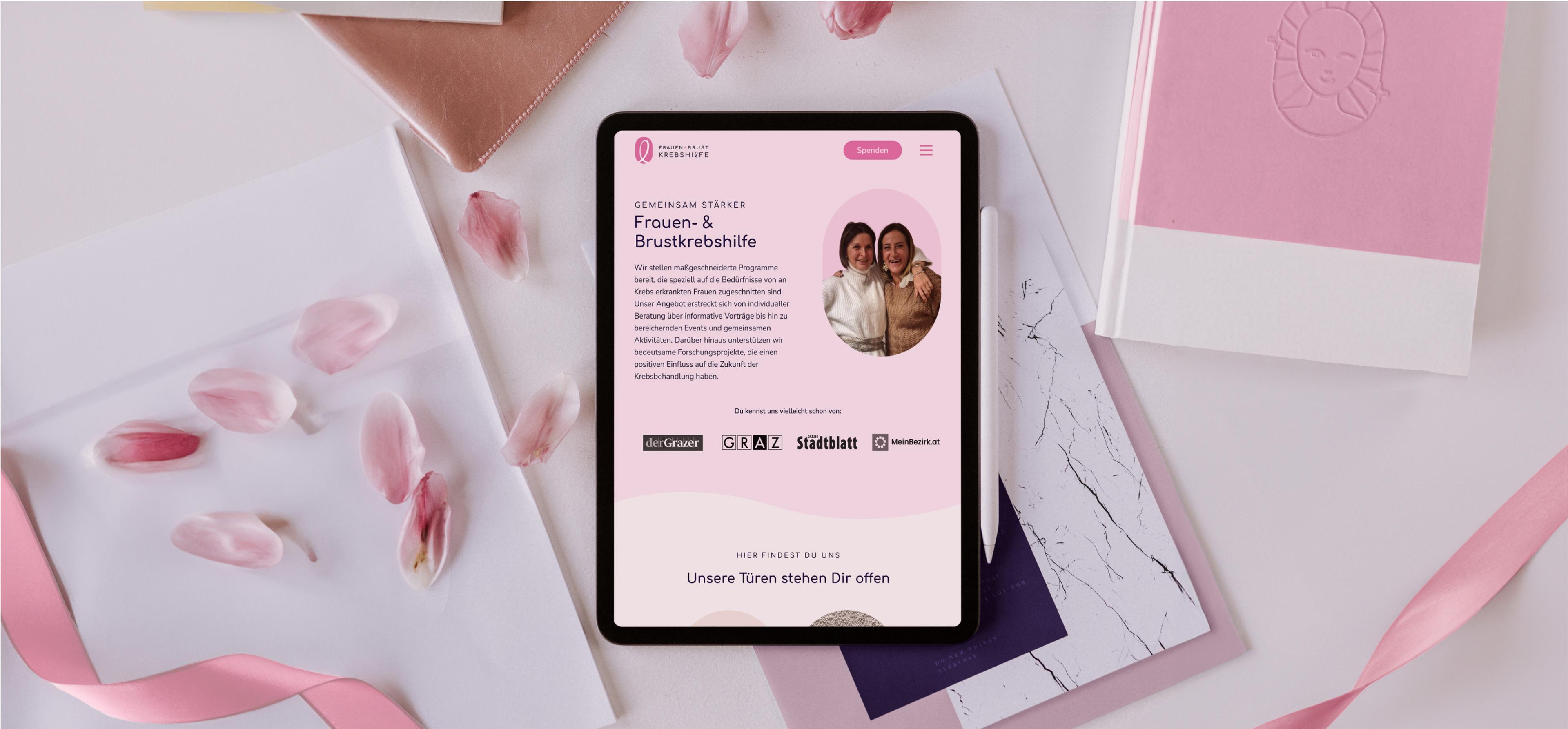 Ein Tablet zeigt die Teamseite der Zauberfrauen-Website. Das Design ist rosa und enthält ein Foto des Teams.