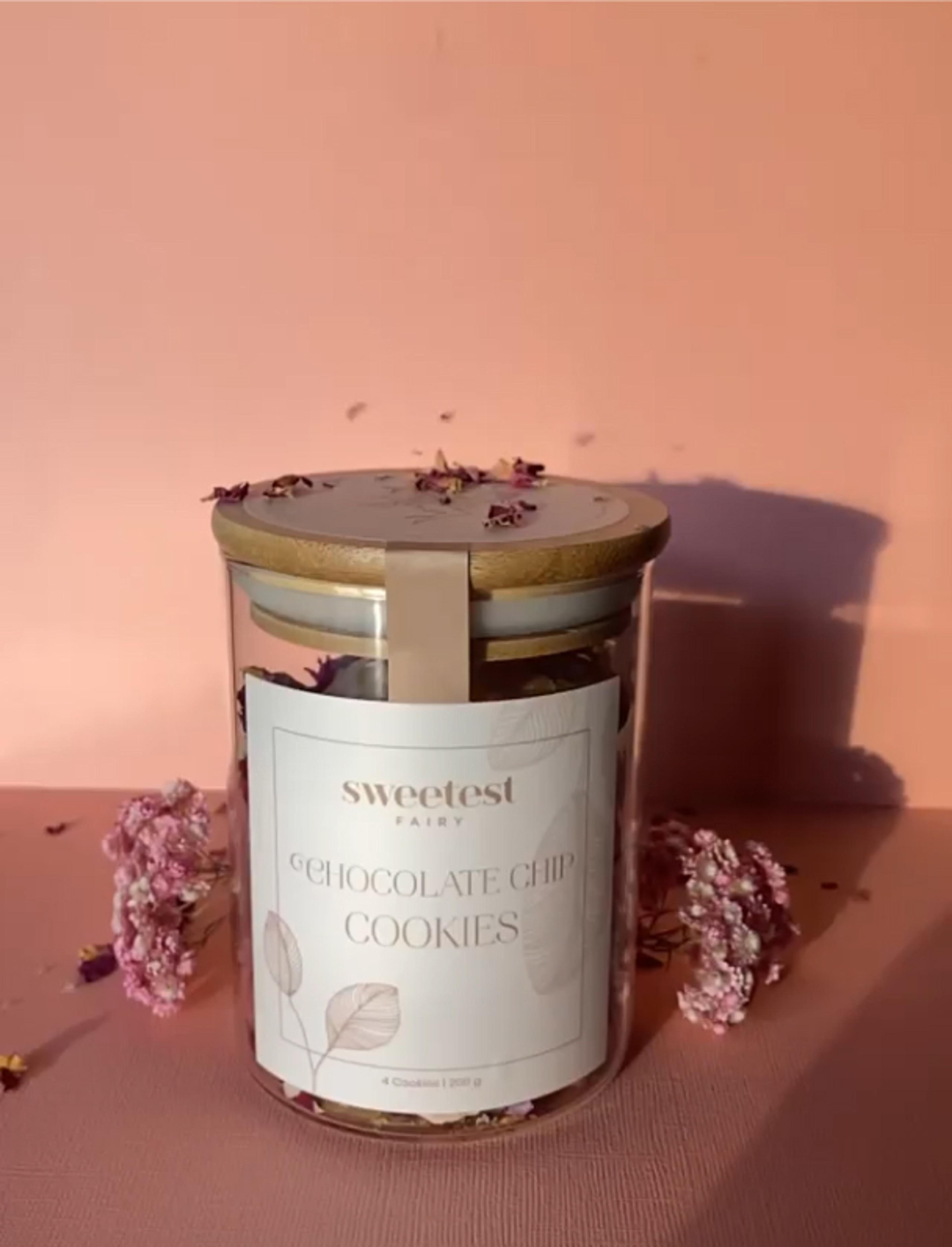 Sweetest Fairy | Sarah Frost Handgemachte Schokoladenkekse mit großen Schokoladenstücken in einer hochwertigen Glasverpackung mit Holzdeckel. Nachhaltiges Verpackungsdesign mit feiner Typografie und elegantem Branding, ideal für Feinkostmarken, Geschenkverpackungen und Premium-Bäckereien. Stilvolle Produktpräsentation für edle Feinkostprodukte. Konzipiert von Unerwartet Branding und Design OG aus Graz, Österreich.