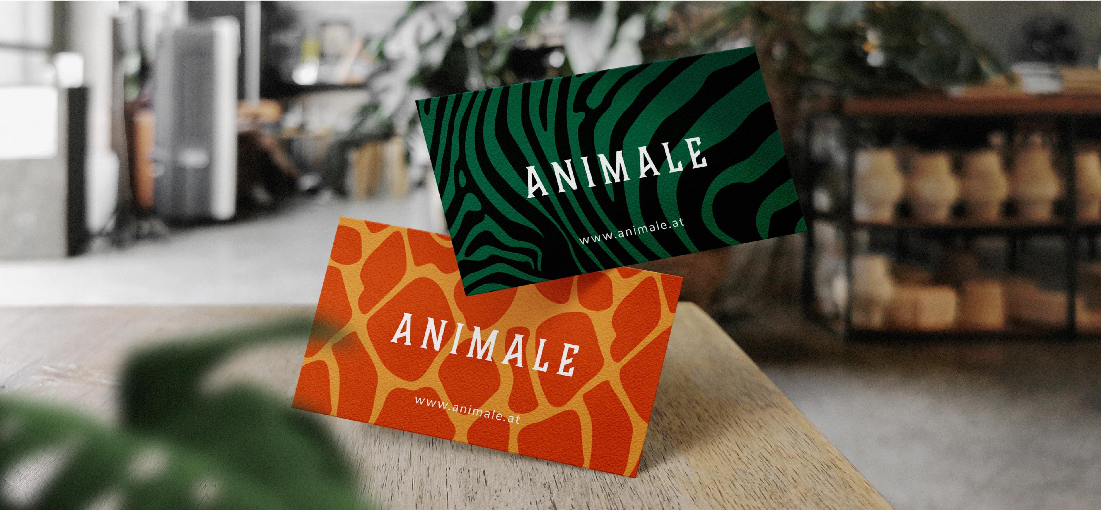 Zwei Visitenkarten für das Restaurant Animale, eine mit grünem Zebramuster, die andere mit orange-gelbem Giraffenmuster.