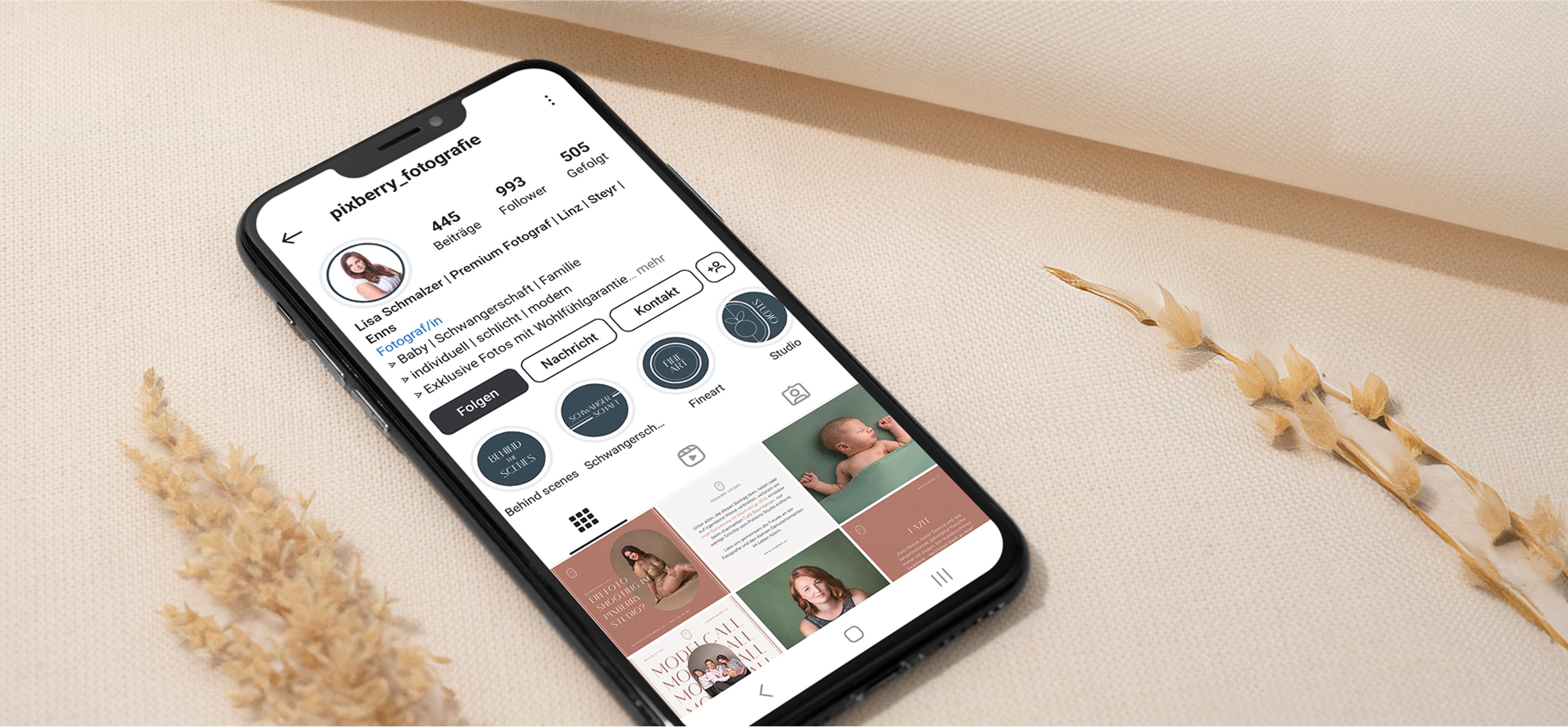 Smartphone mit Instagram-Profil von Pixberry Fotografie auf beigem Stoff – Ein Smartphone zeigt das Instagram-Profil von Pixberry Fotografie mit einem ästhetischen Feed und durchdachtem Branding. Im Hintergrund liegen Trockenblumen auf Stoff.