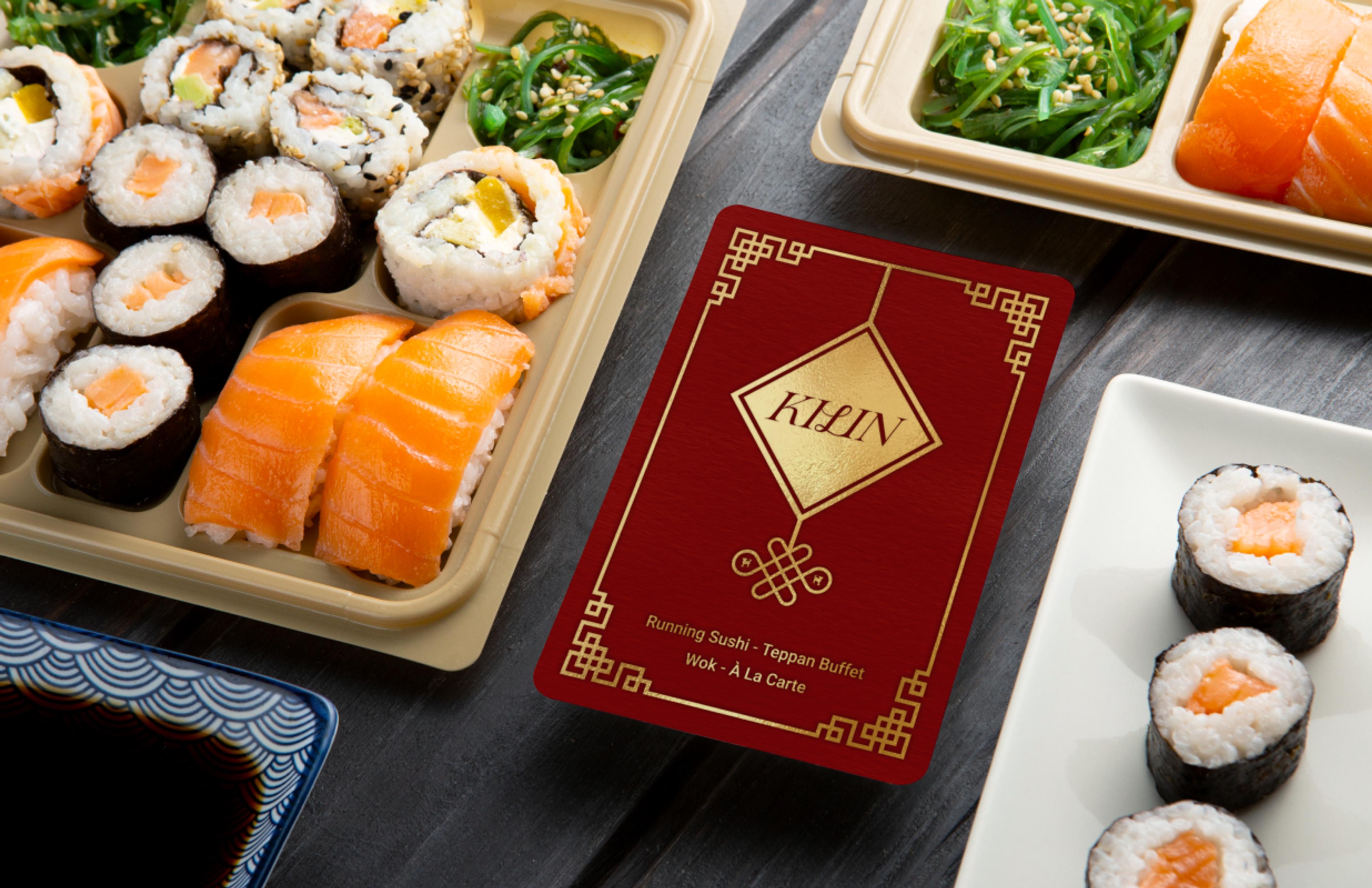 Exklusiver Geschenkgutschein des Kilin Restaurants im luxuriösen Design mit Goldprägung und asiatischen Mustern, stilvoll arrangiert mit Sushi, Algensalat und Wasabi auf einer Schieferplatte. Hochwertiges Branding für Premium-Gastronomie mit edler Farbgestaltung und durchdachter Markenstrategie. Konzipiert von Unerwartet Branding und Design OG aus Graz, Österreich.