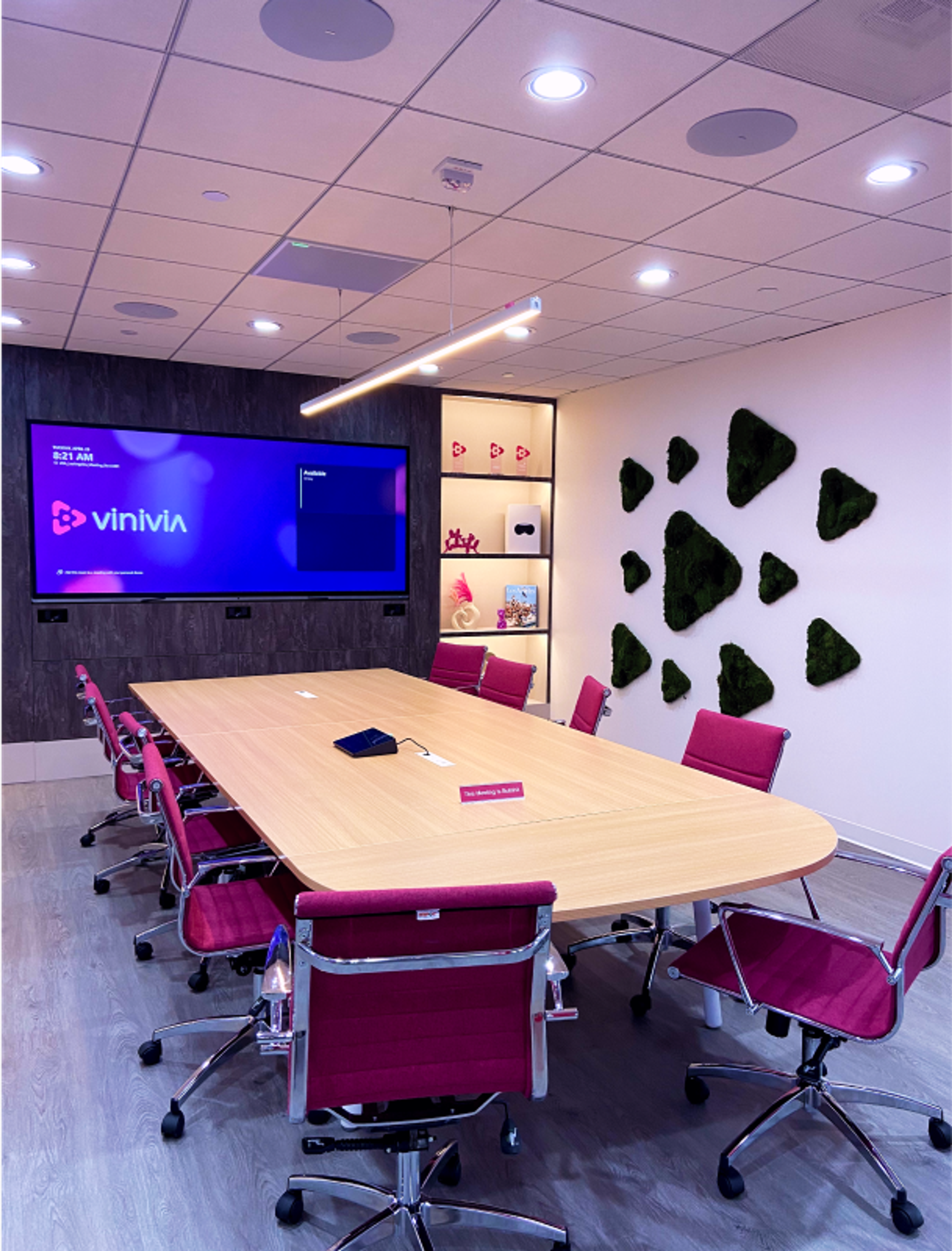 Modern eingerichteter Meetingraum im Vinivia Office in Los Angeles mit bepflanzten Wandakzenten, großem Holztisch und integriertem Bildschirm – Unerwartet Design