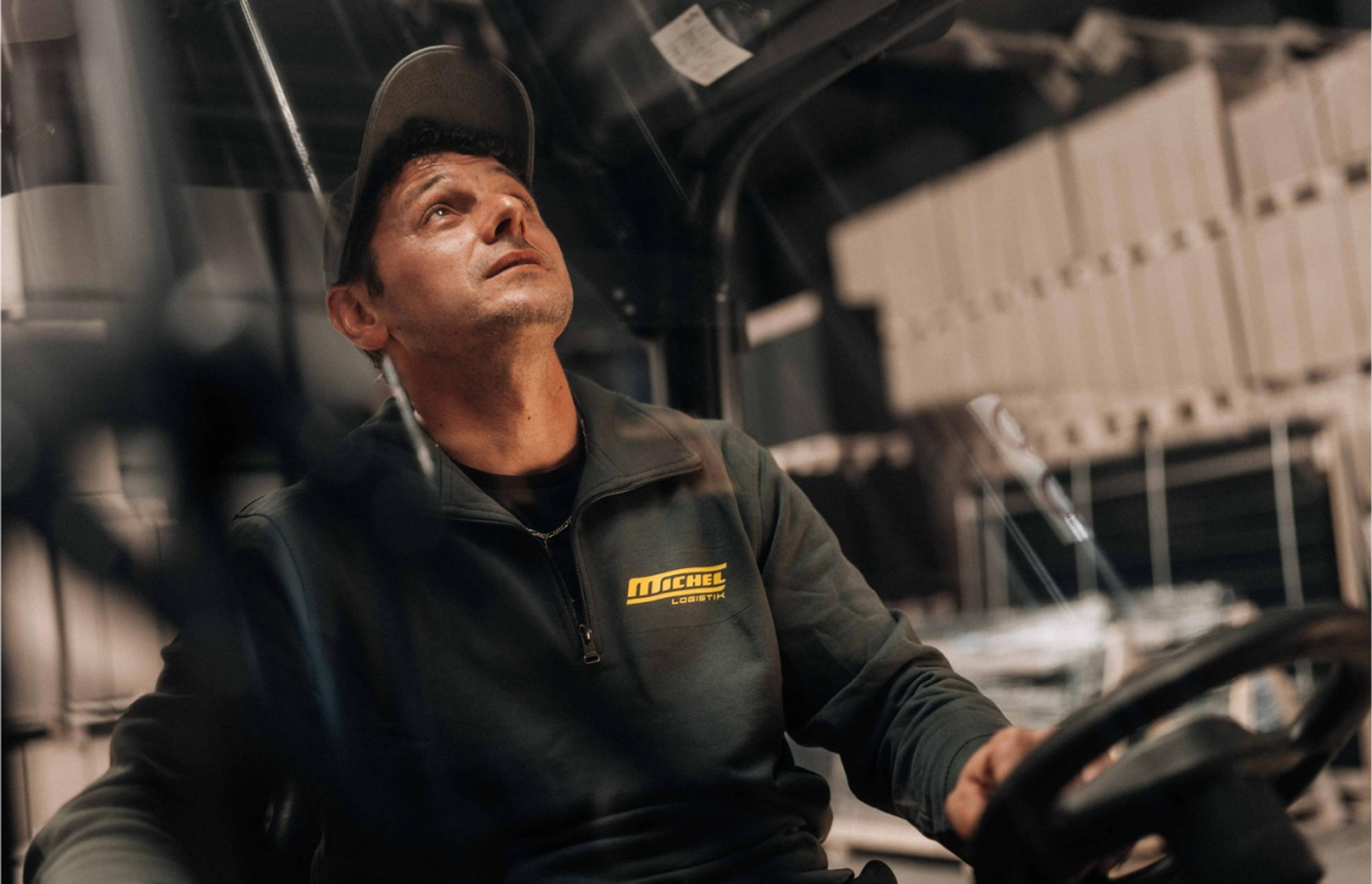 WOODS Consulting, Leopold Michel GmbH Michel Logistik Fahrer in Arbeitskleidung mit Logo, fotografiert in seinem Fahrzeug – Corporate Identity und Fotografie von Unerwartet Design.