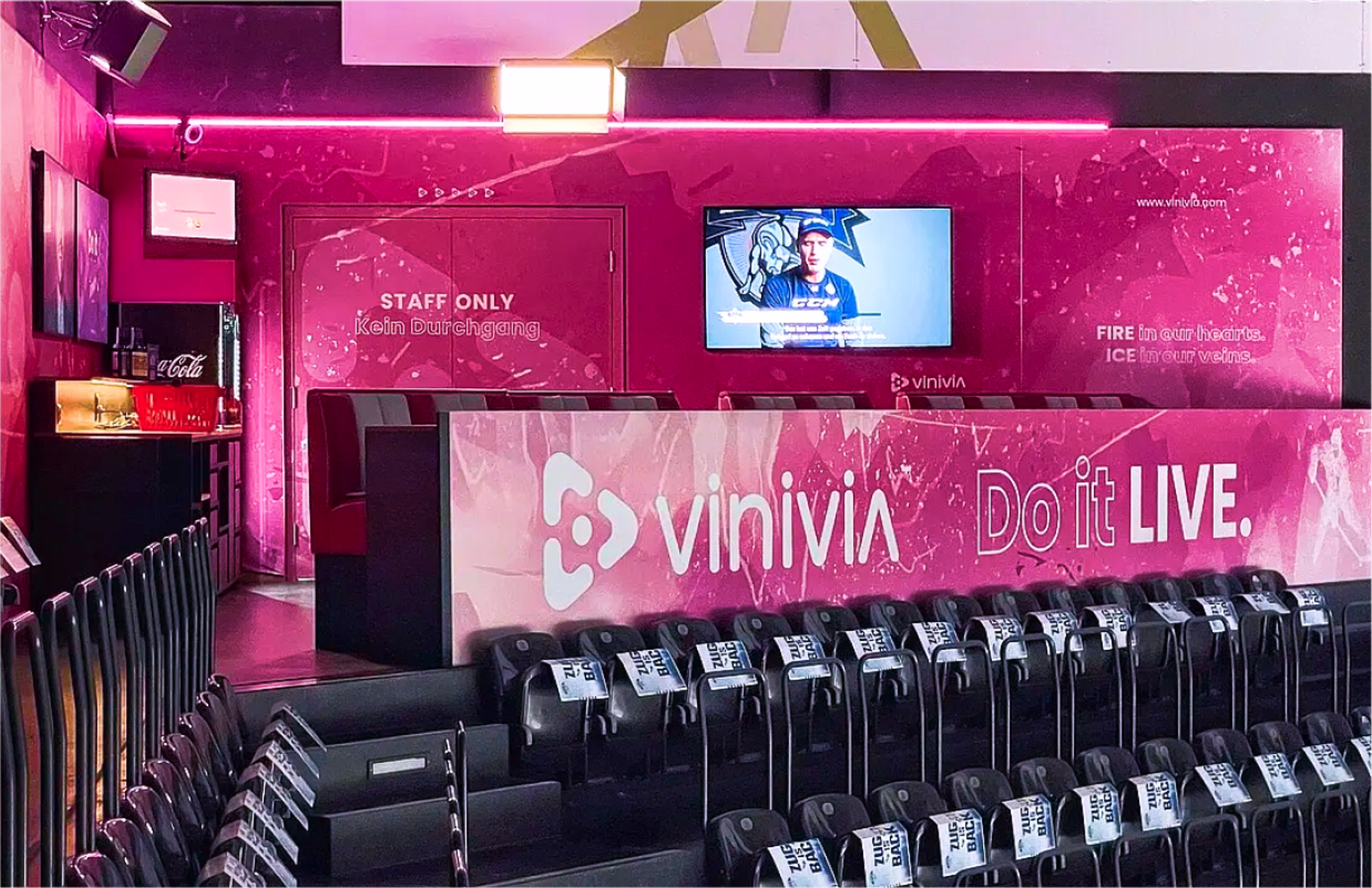 Modern gestaltete Lounge mit pinkfarbenen Wänden, Vinivia-Branding und Sitzbereichen für Gäste, inspiriert von Eishockey-Atmosphäre – Unerwartet Design