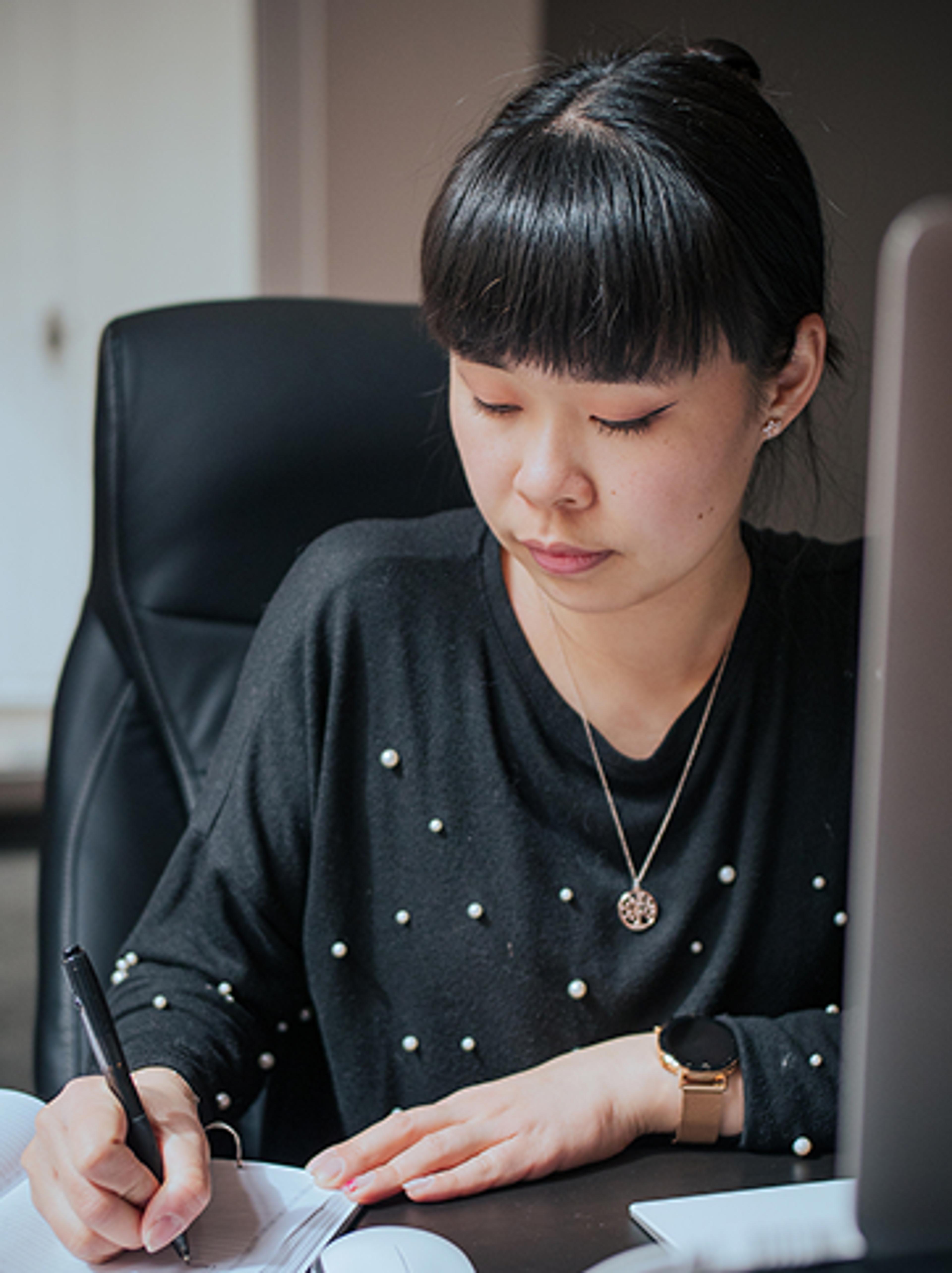 Ijob Brandstätter Nan Lin - Lini - Mitgründerin der Unerwartet Branding und Design Agentur - schreibt ihre täglichen Design-Aufgaben in einen Notizblock. Sie befindet sich in dem hellen schönen Büro der Unerwartet Branding und Design Agentur in der Belgiergasse 16 in Graz, Steiermark, Österreich.