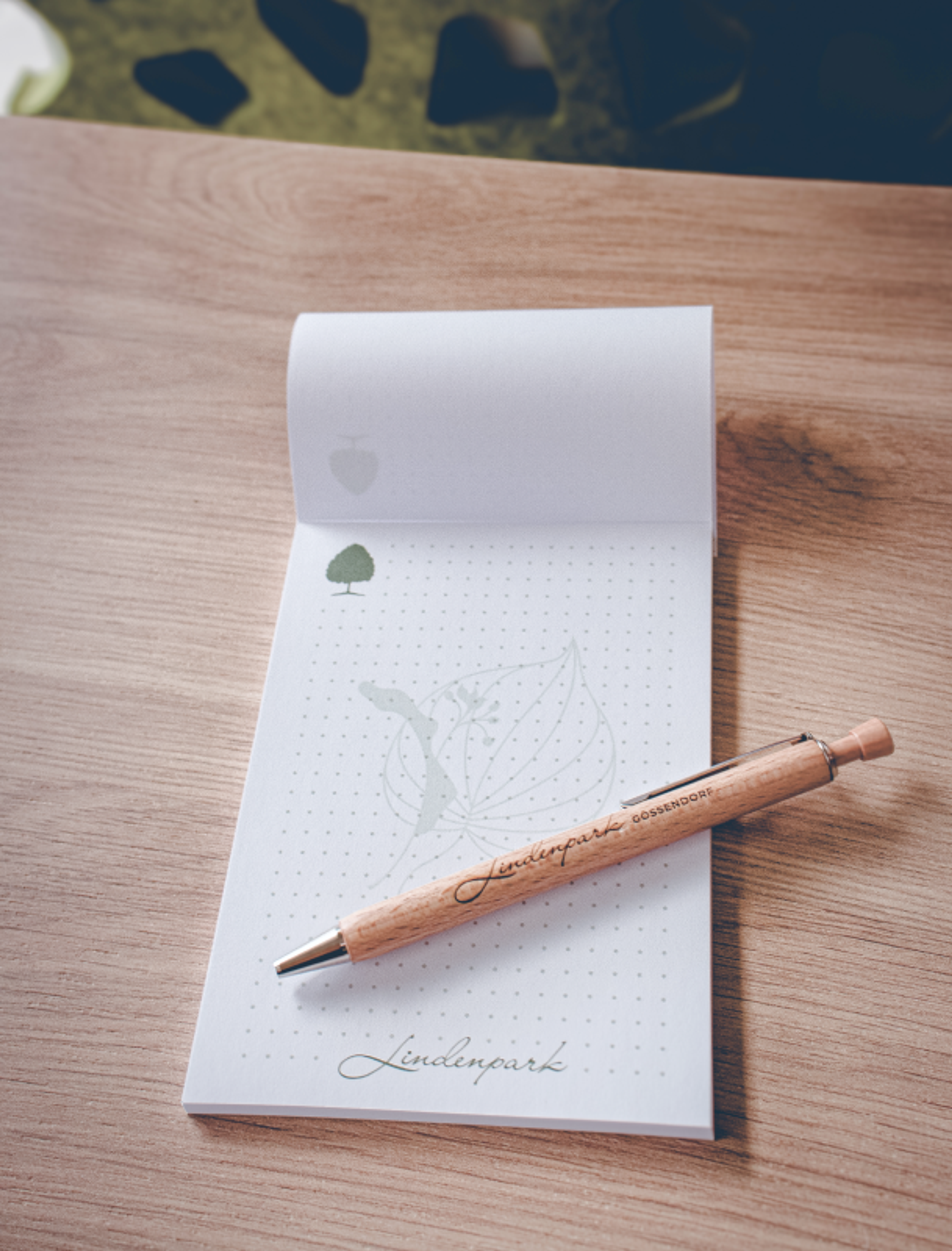 Logo & Grundkonzept BUCHER BRAND MARKETING e.U. Kleiner Notizblock mit Lindenpark-Logo und passendem Holzkugelschreiber, gestaltet von Unerwartet Design.