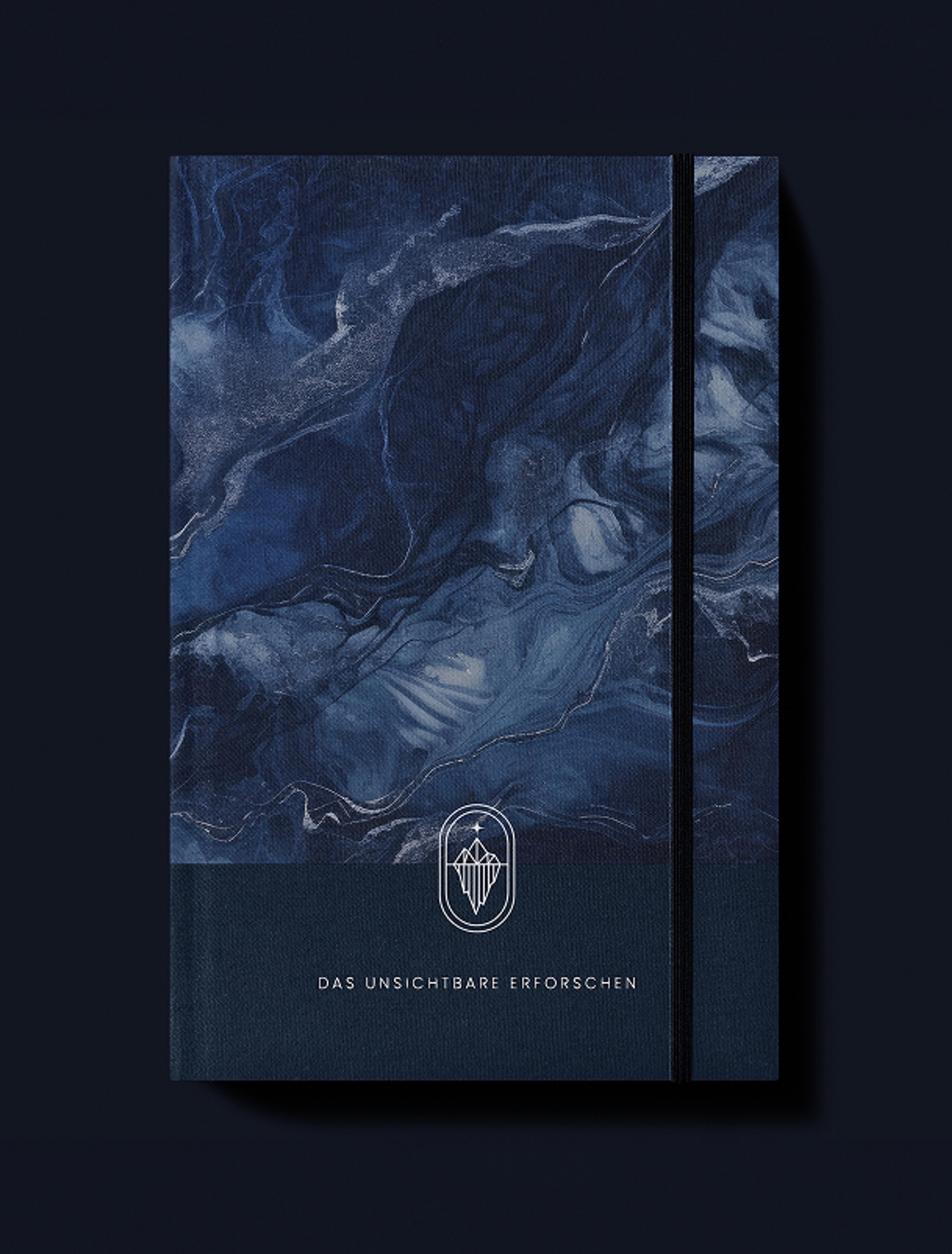 Ein dunkelblaues Notizbuch mit marmorierter Struktur, verziert mit einem feinen Eisberg-Logo und dem Schriftzug „Das Unsichtbare Erforschen“.
