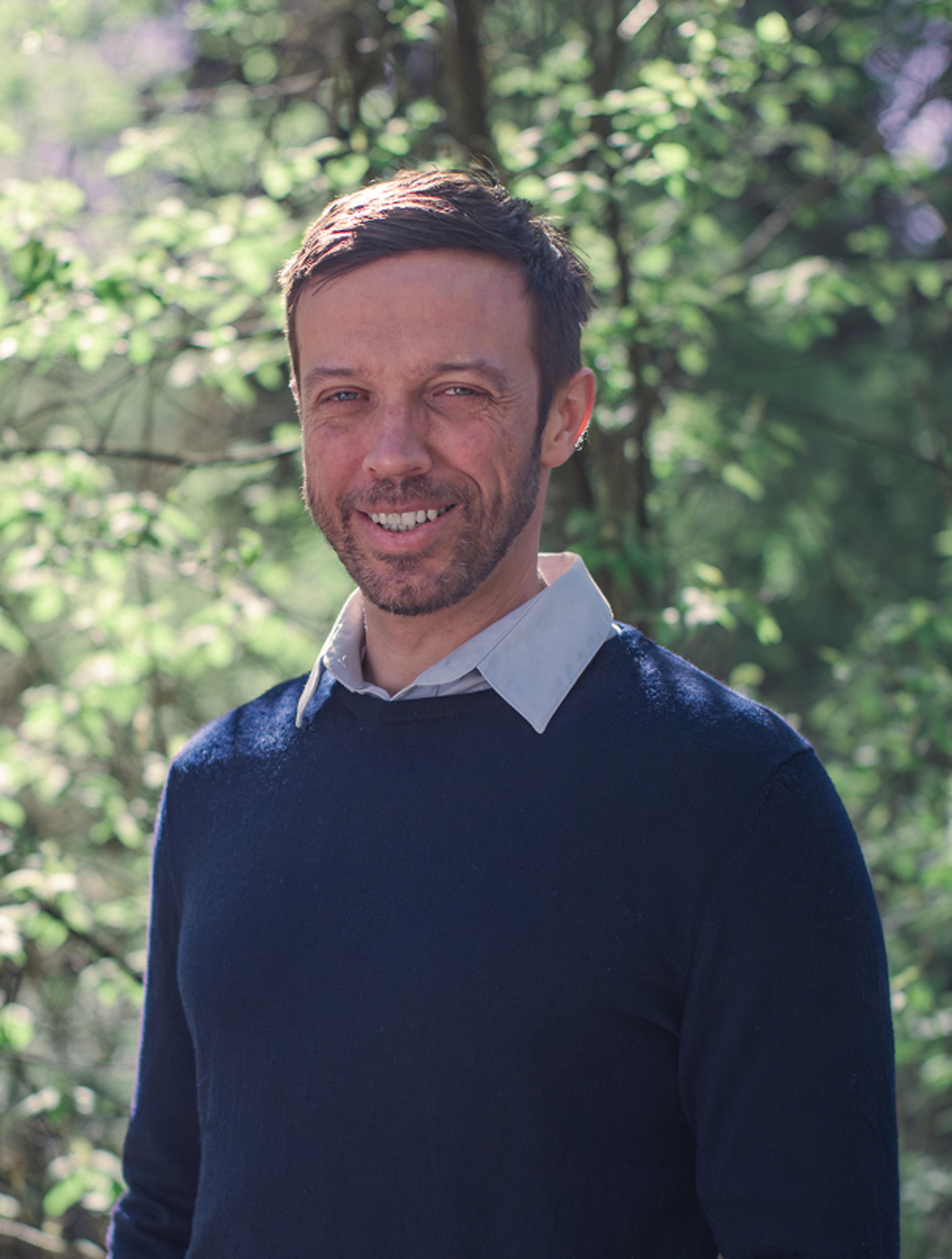 Michael Hansmann, Physiotherapeut & Osteopath, im Grünen. Professionelles, authentisches Porträt für das Branding von Physio Hansmann & Lindenpark Gössendorf.