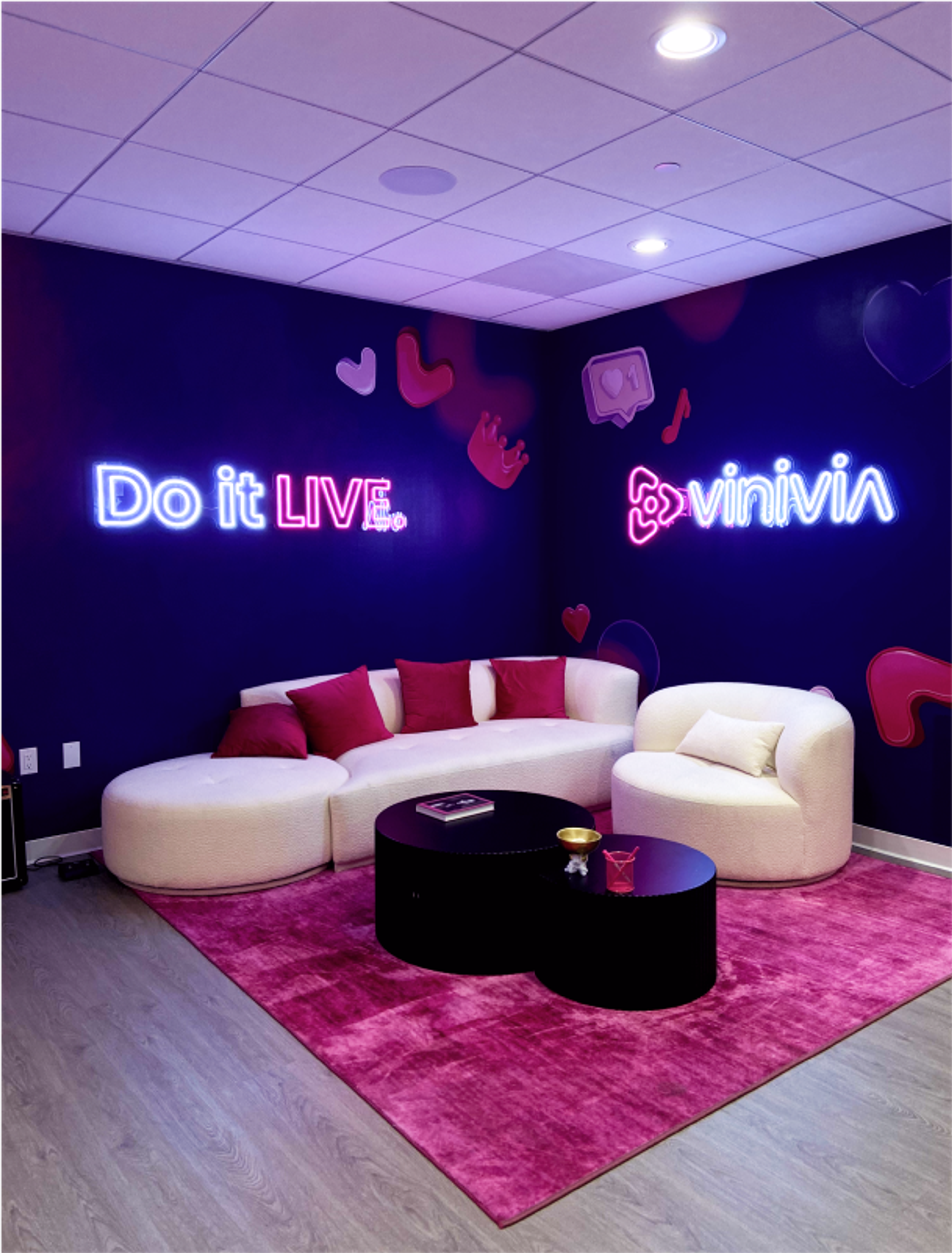 Einladender Eingangsbereich im Vinivia Office in Los Angeles mit komfortablen Möbeln, pinkem Teppich und beleuchteten „Do it LIVE“- und Vinivia-Logos – Unerwartet Design
