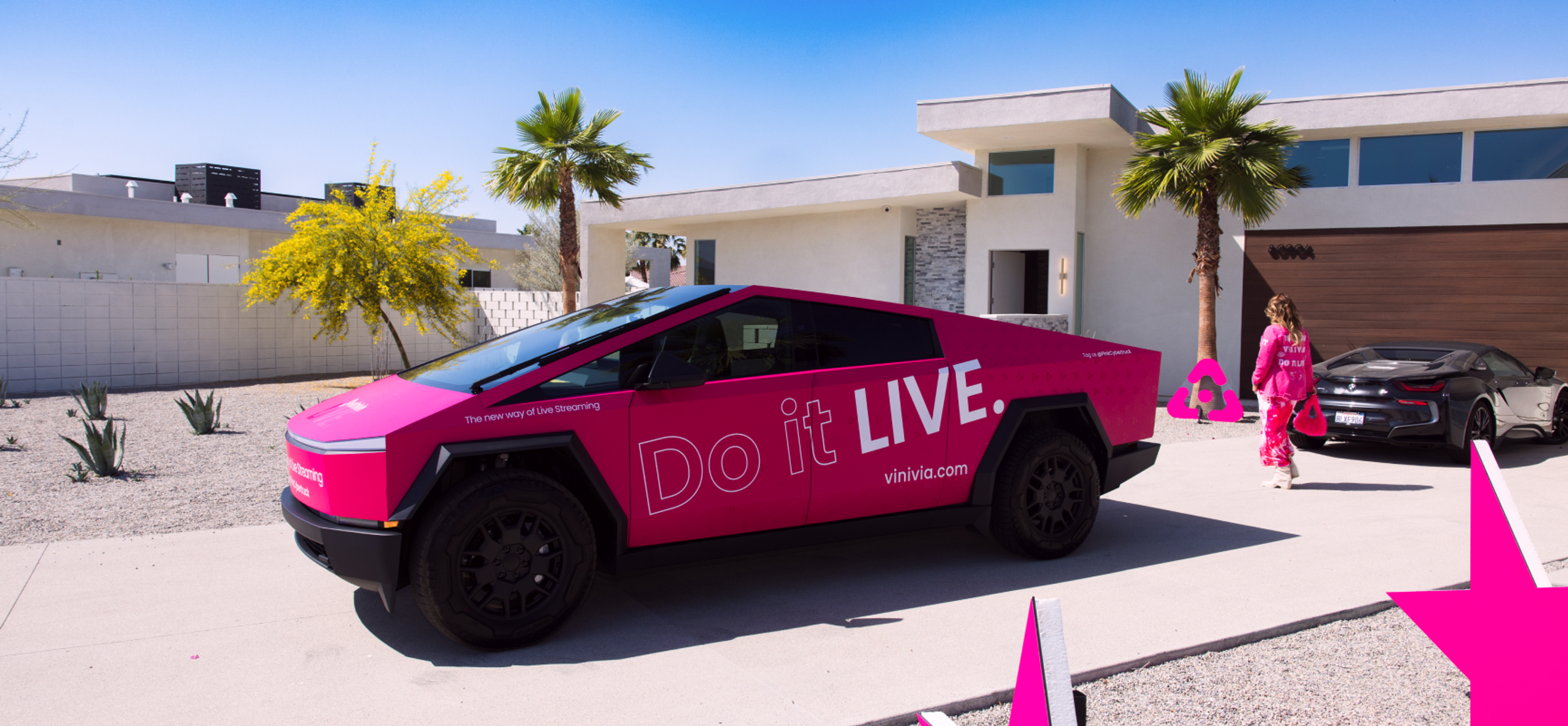 vinivia Elektrofahrzeug im modernen Vinivia-Design, geparkt vor einer luxuriösen Villa, mit pinkfarbenen Akzenten und "Do it LIVE"-Branding - Unerwartet Design
